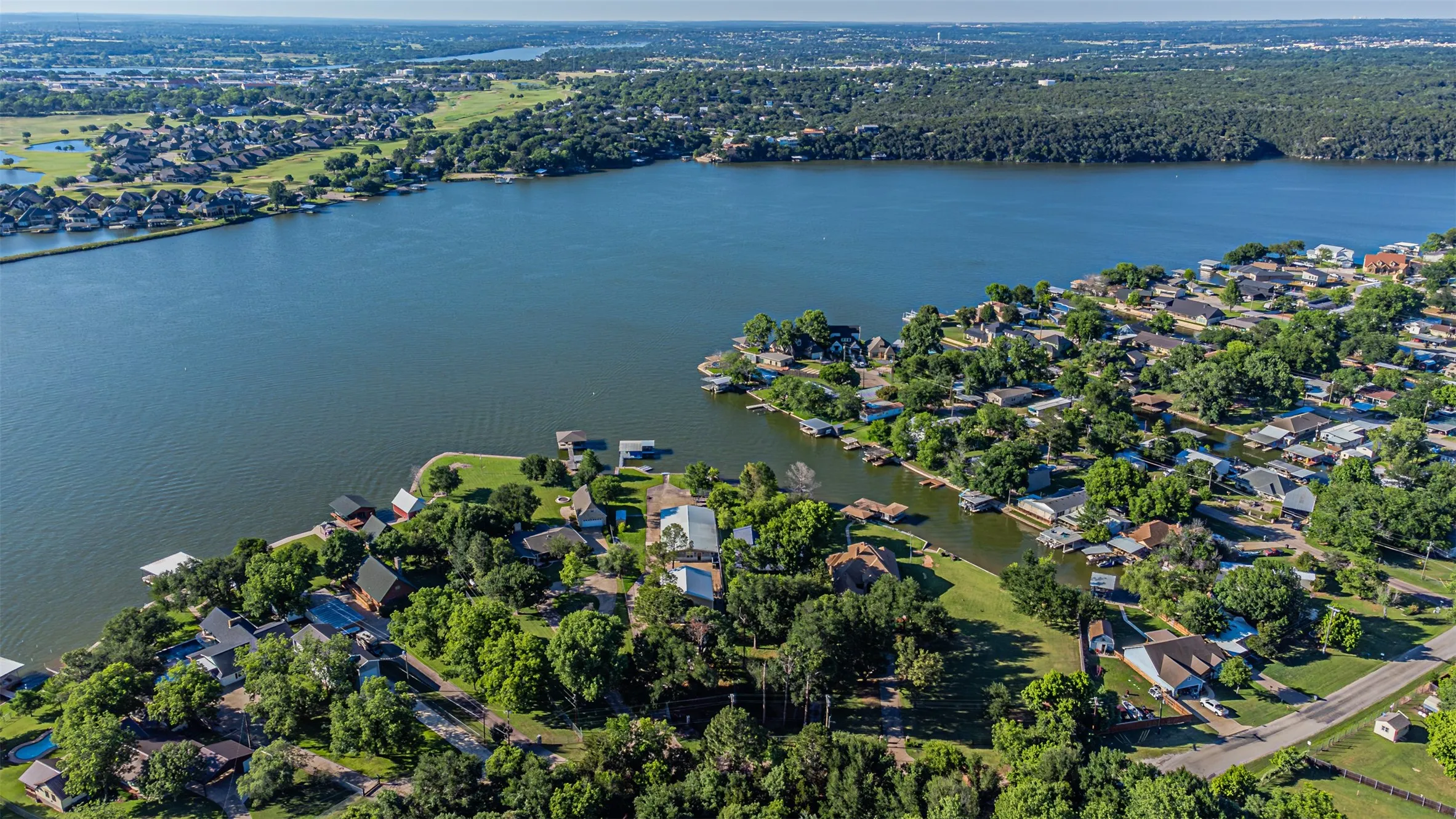 Aerial perspective showcasing waterfront properties, extensive tree coverage, and a large body of water