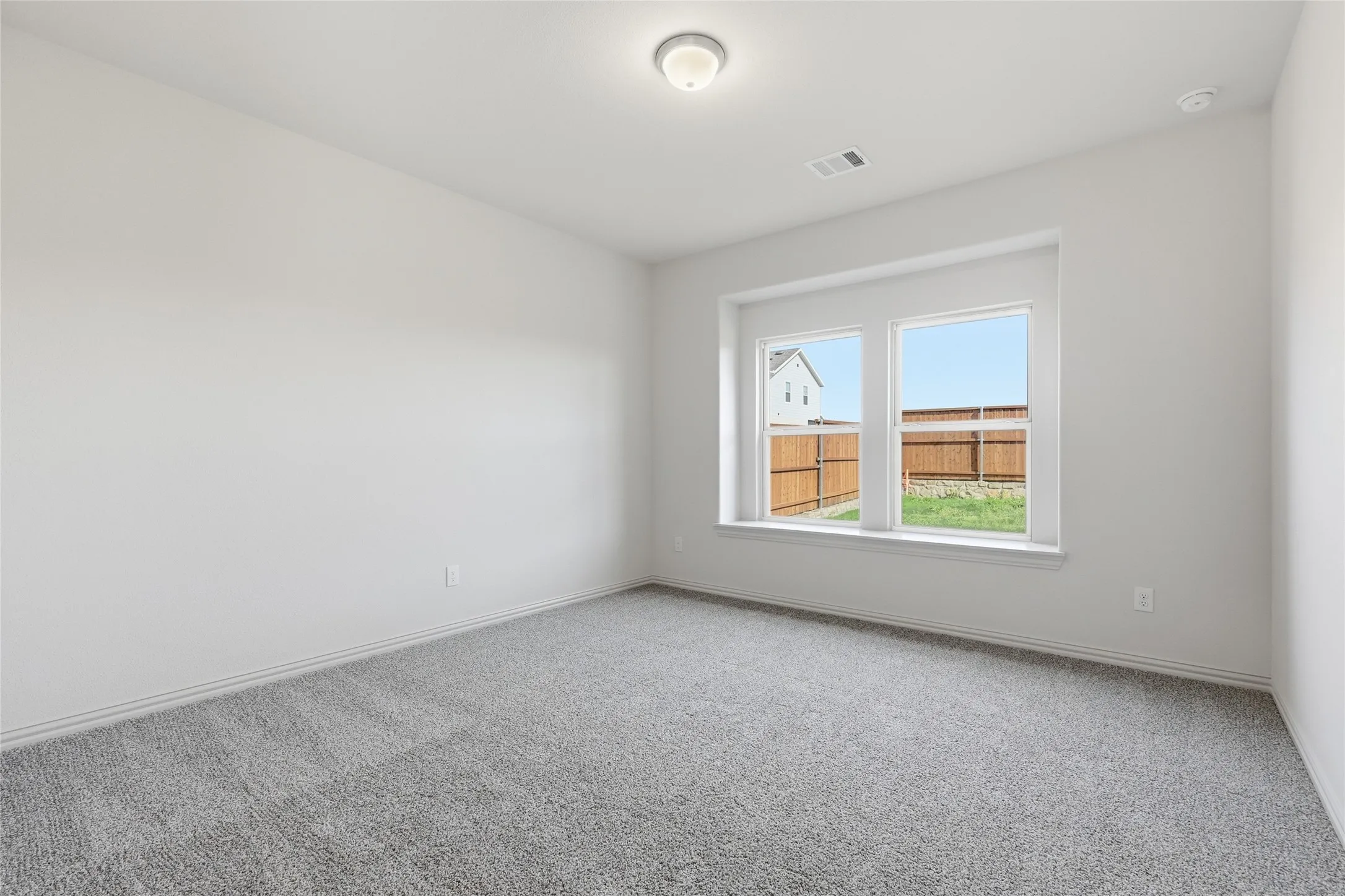 Bright interior space featuring a double window, light gray carpeting, neutral wall tones, and a ceiling-mounted light fixture