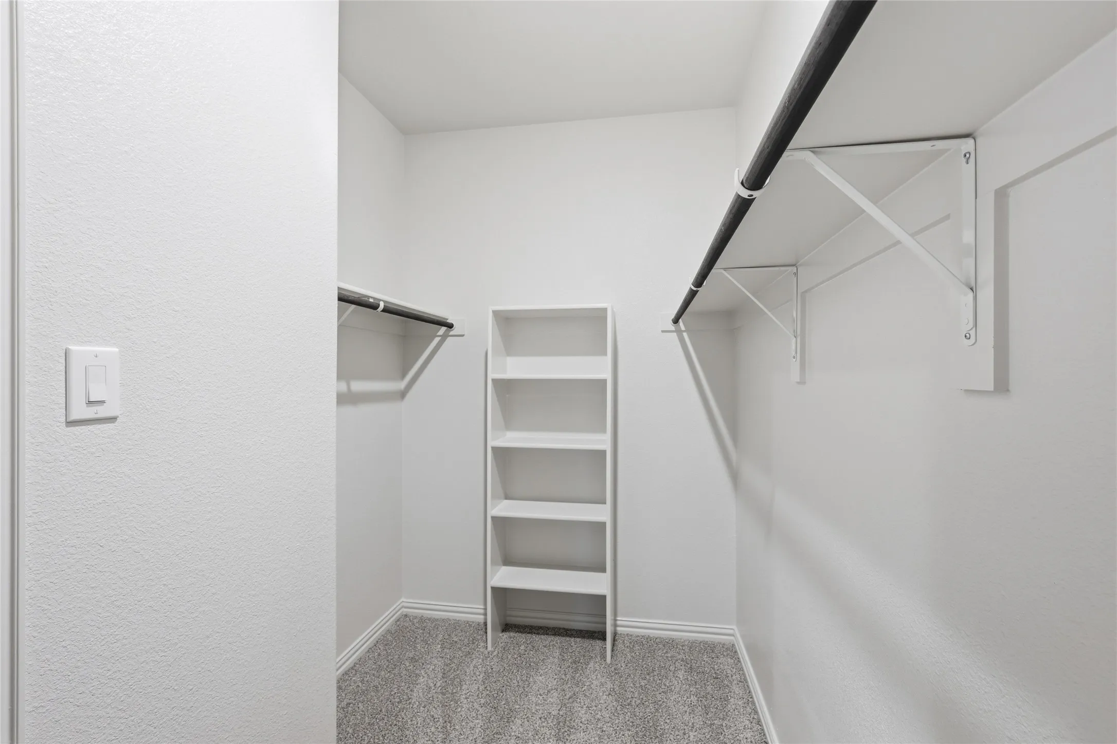 Walk-in closet featuring carpet flooring, built-in shelving, and dual hanging rods