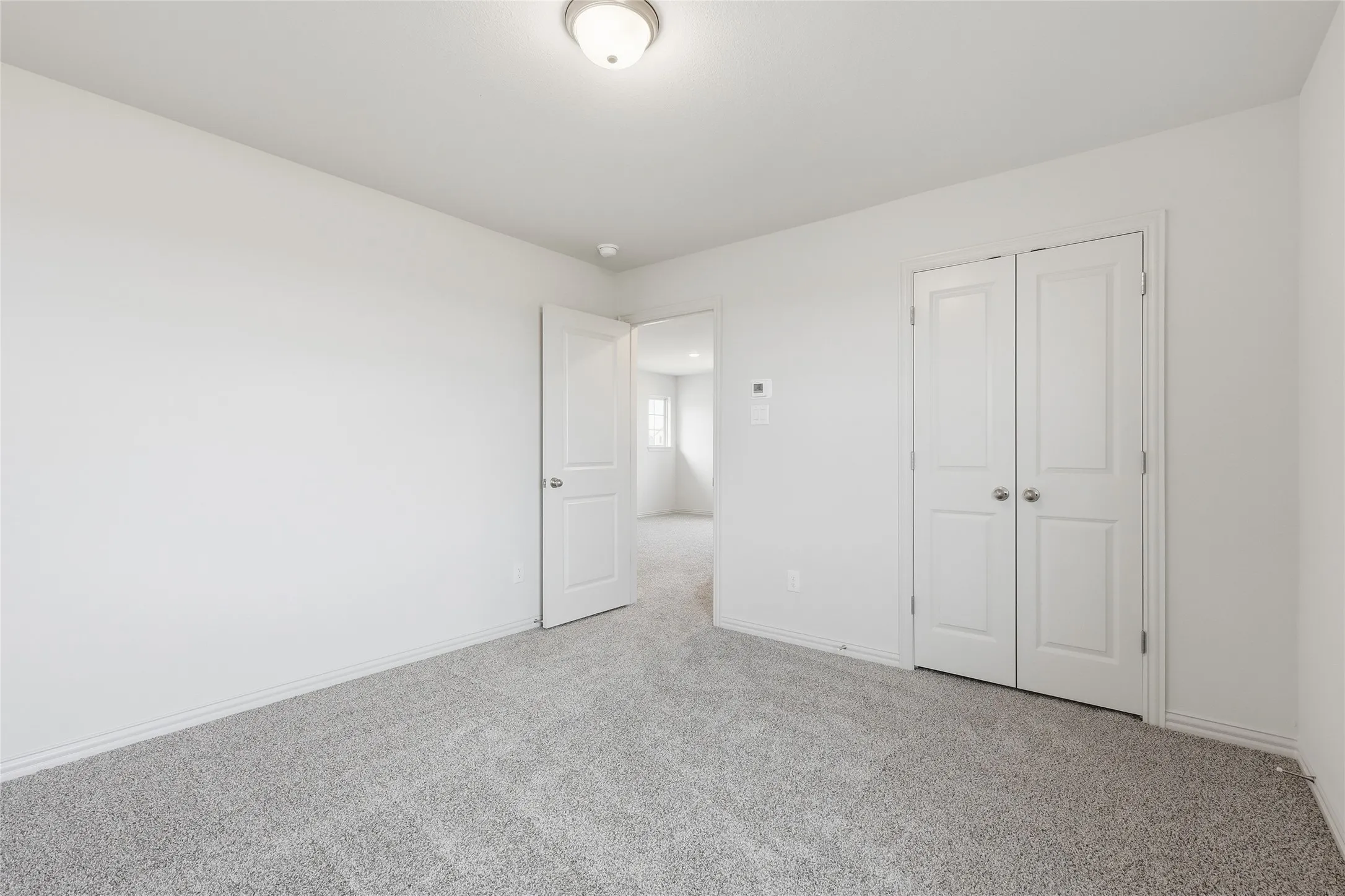 Spacious interior room featuring light-colored walls and grey carpet flooring