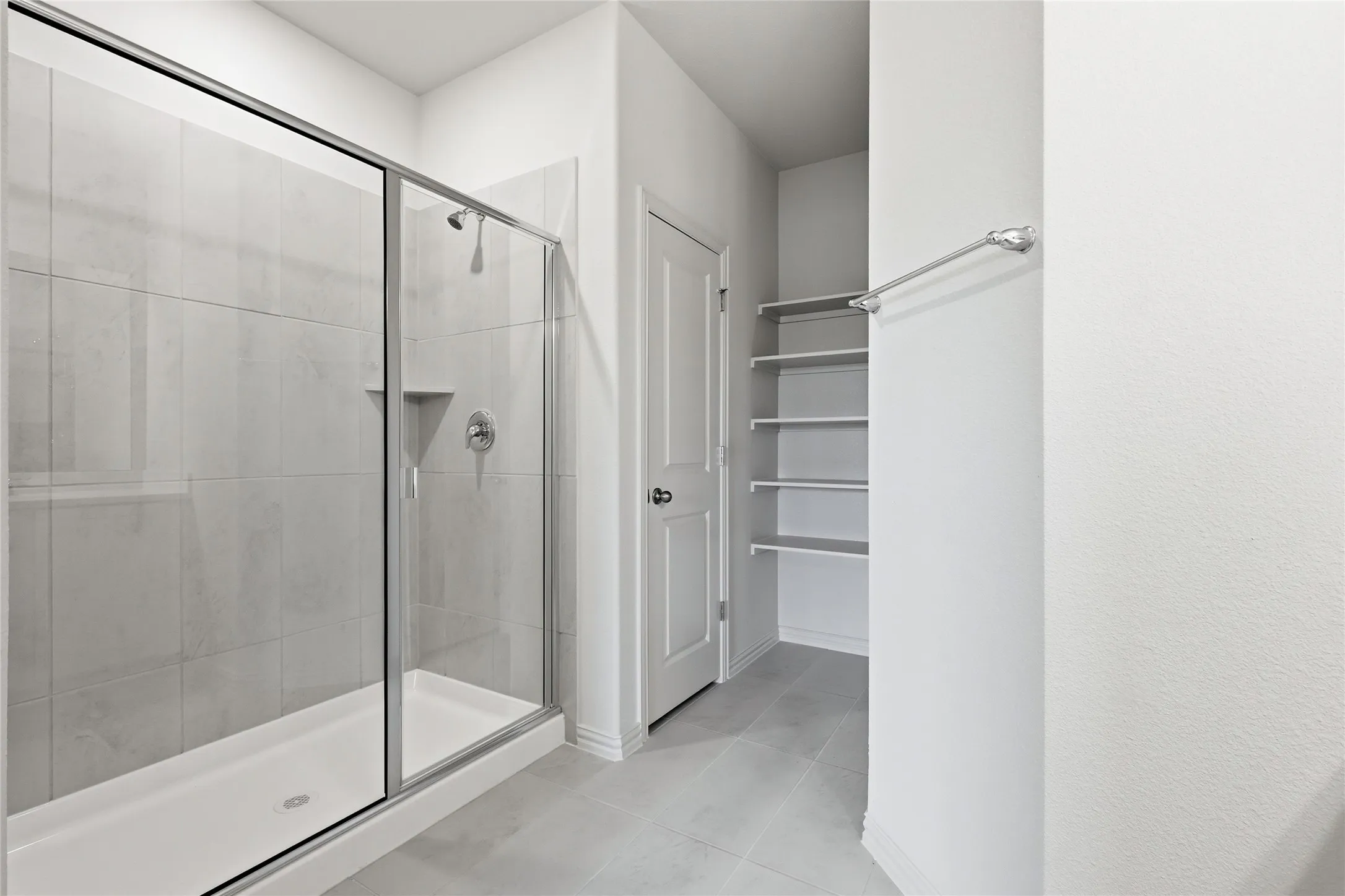 Walk-in shower with clear glass enclosure and tile surround