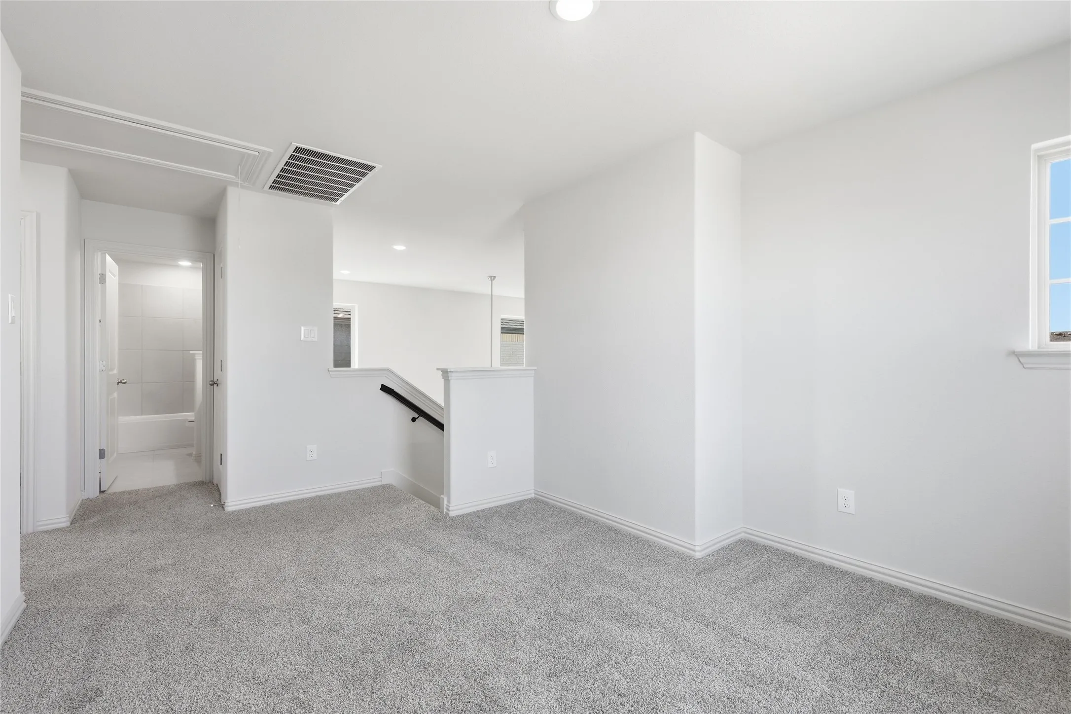 Carpeted room with a window providing natural illumination, complemented by an overhead light fixture