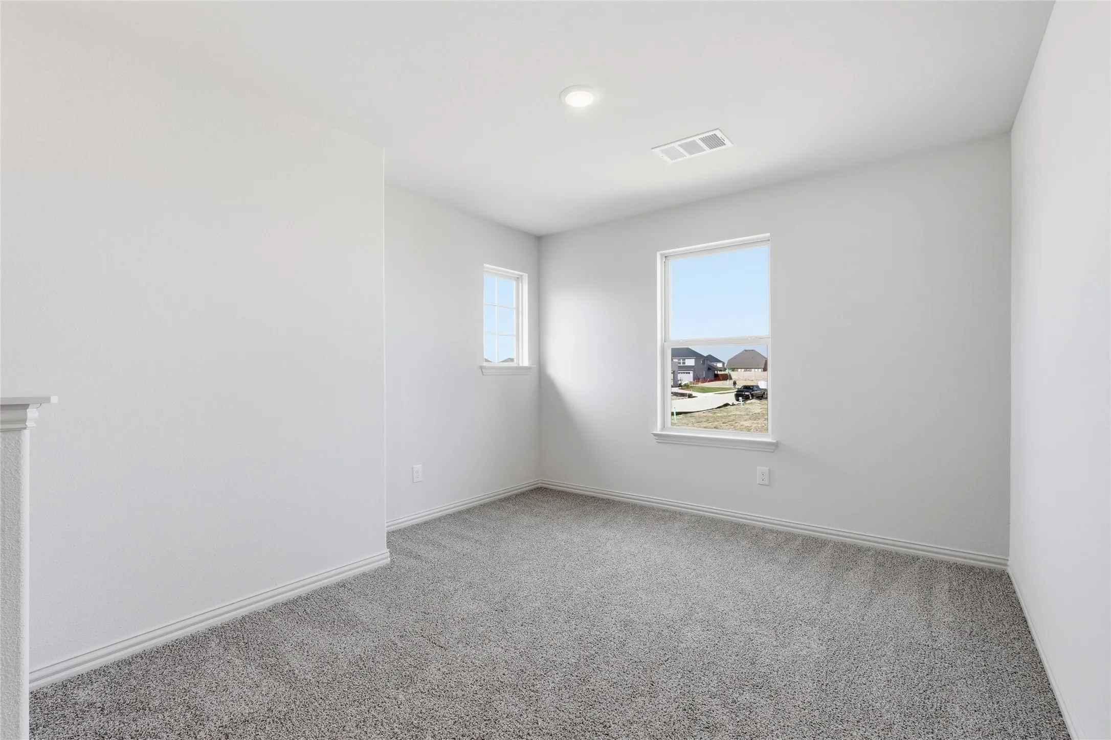 Bright interior space featuring light gray carpeting, crisp white walls, and two windows