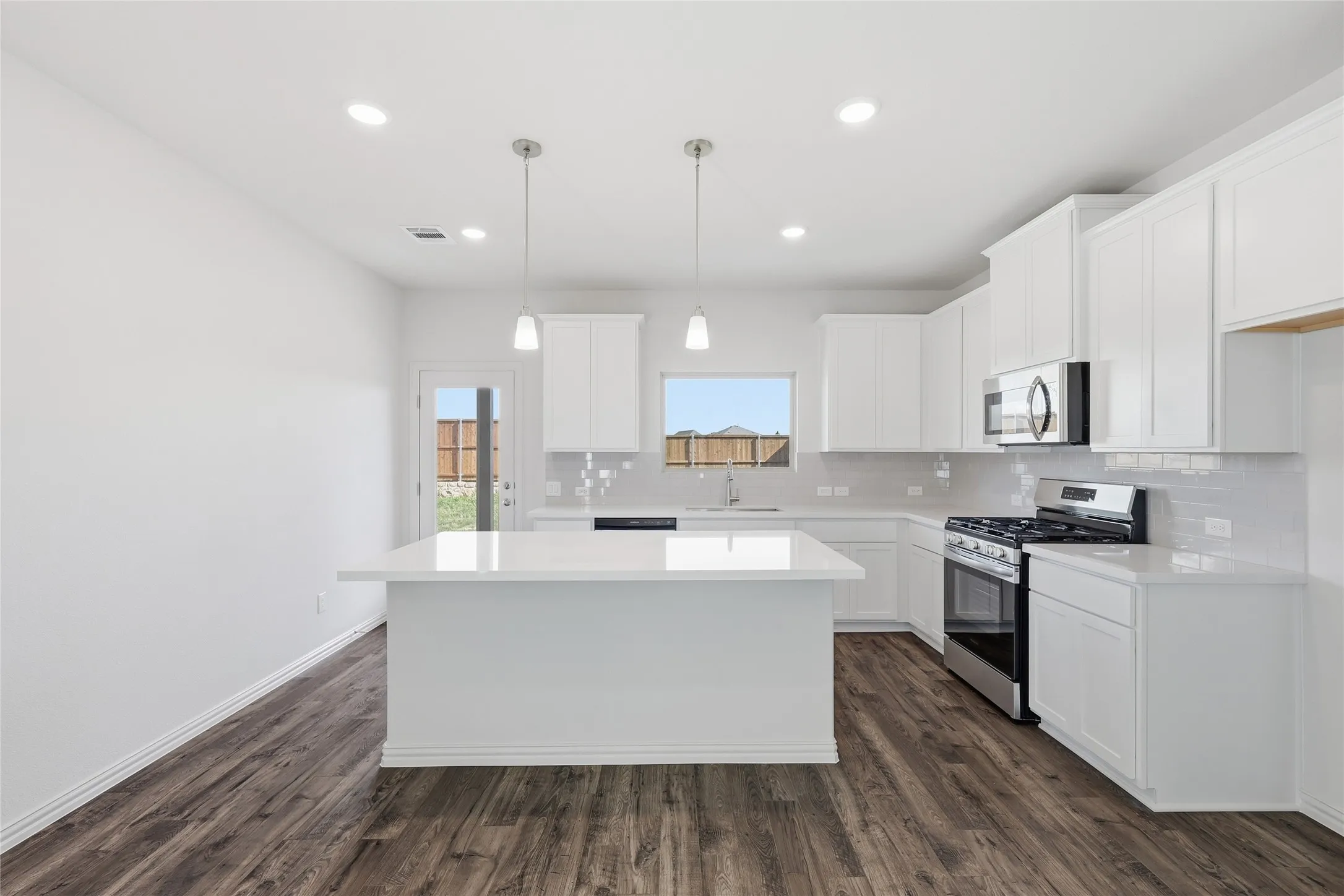 Contemporary kitchen featuring an island, white cabinetry, stainless steel appliances, wood-finish flooring, and recessed lighting
