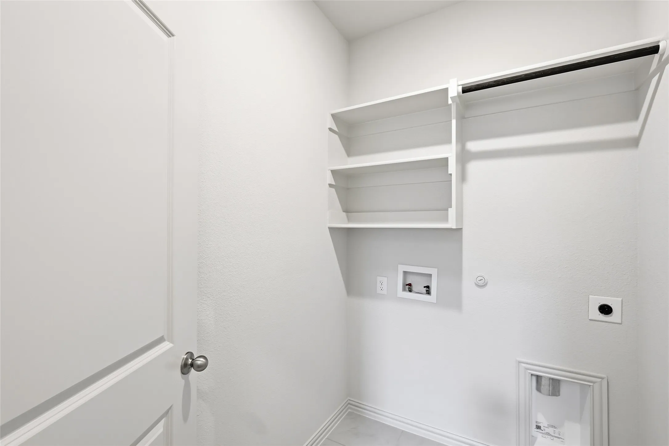 Utility room featuring built-in shelving, a garment rod, and plumbing hookups