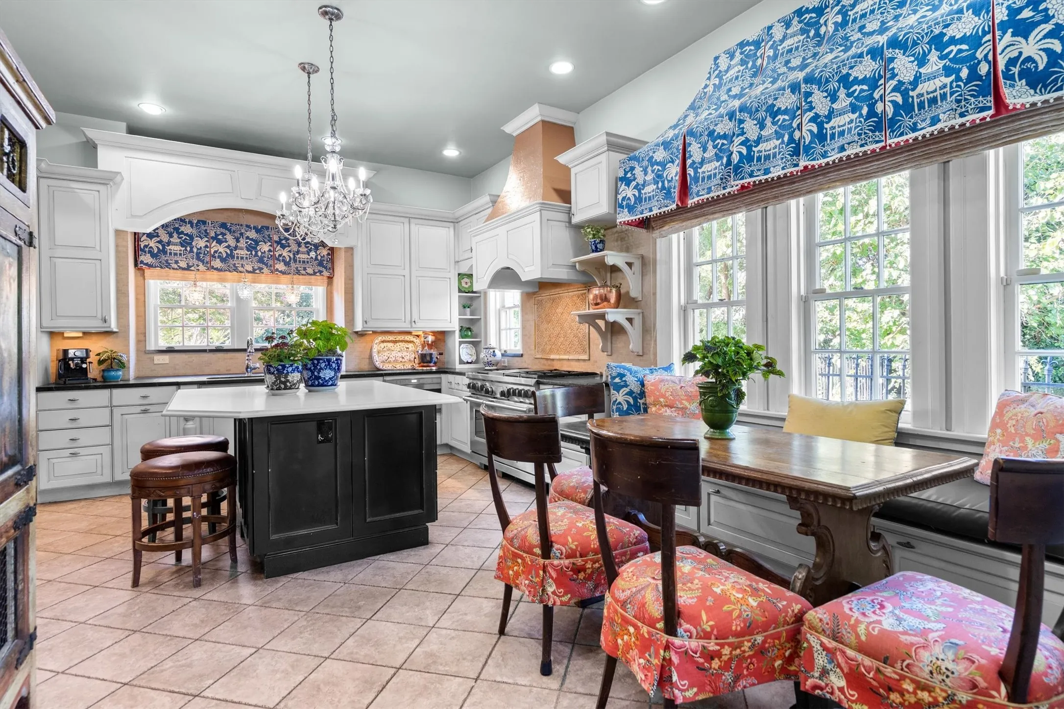 The timeless kitchen showcases a spacious
breakfast bar, patterned tile floors, stylish
backsplash, designer light fixtures, and a premium
high-end range.