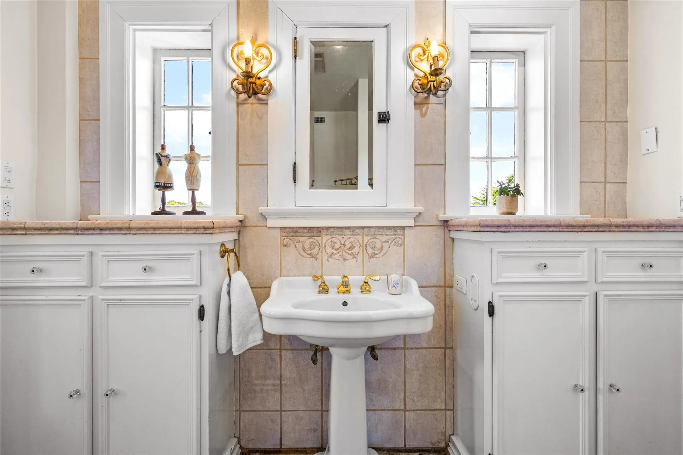This beautifully appointed bathroom features an elegant tile backsplash, dual sinks for convenience,
and unique sconces that add a touch of artistic flair and ambient lighting.