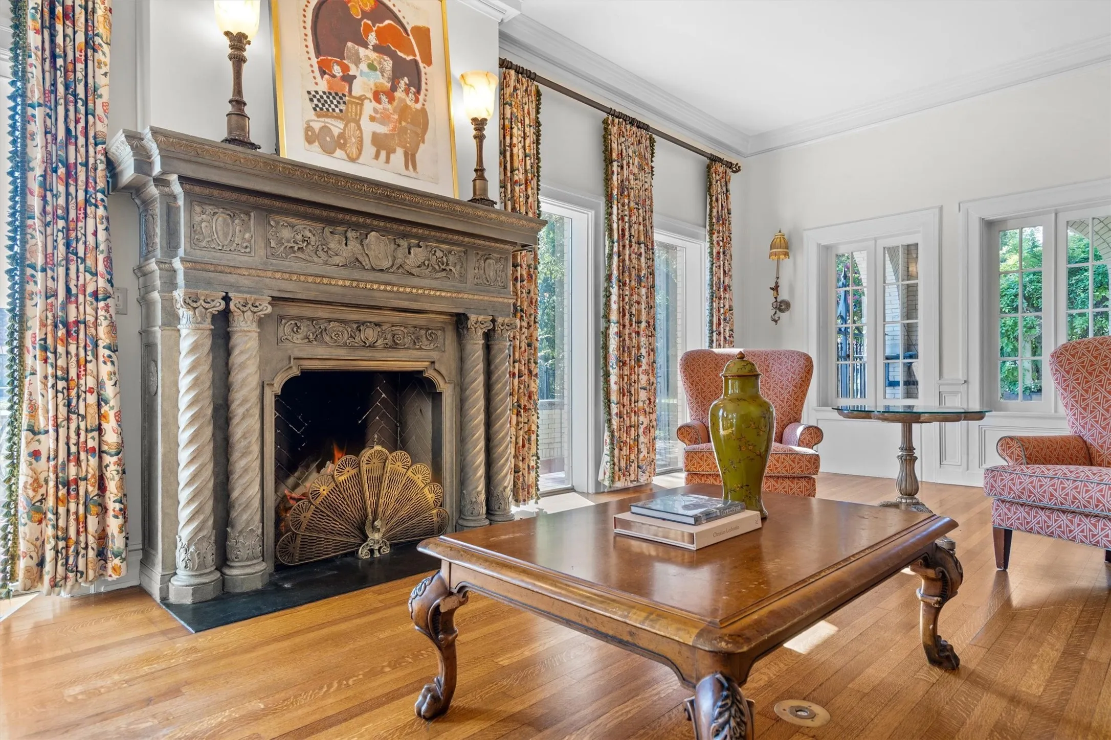 This inviting living room features a stunning hand
carved fireplace with intricate detailing, warm hardwood floors, and abundant natural light, creating an elegant yet comfortable space for gathering.