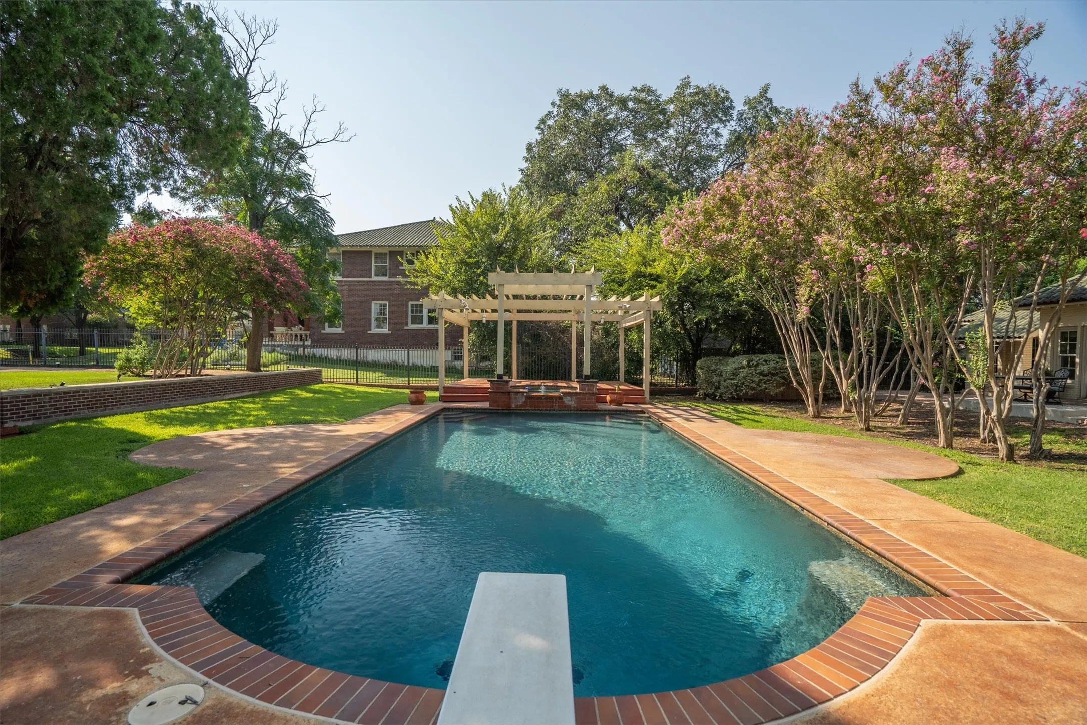 Enjoy endless fun and relaxation at this backyard
retreat, where you can swim from the pool to the
connected hot tub, dive off the board, lounge on
the patio, or unwind in the shade of the pergola.