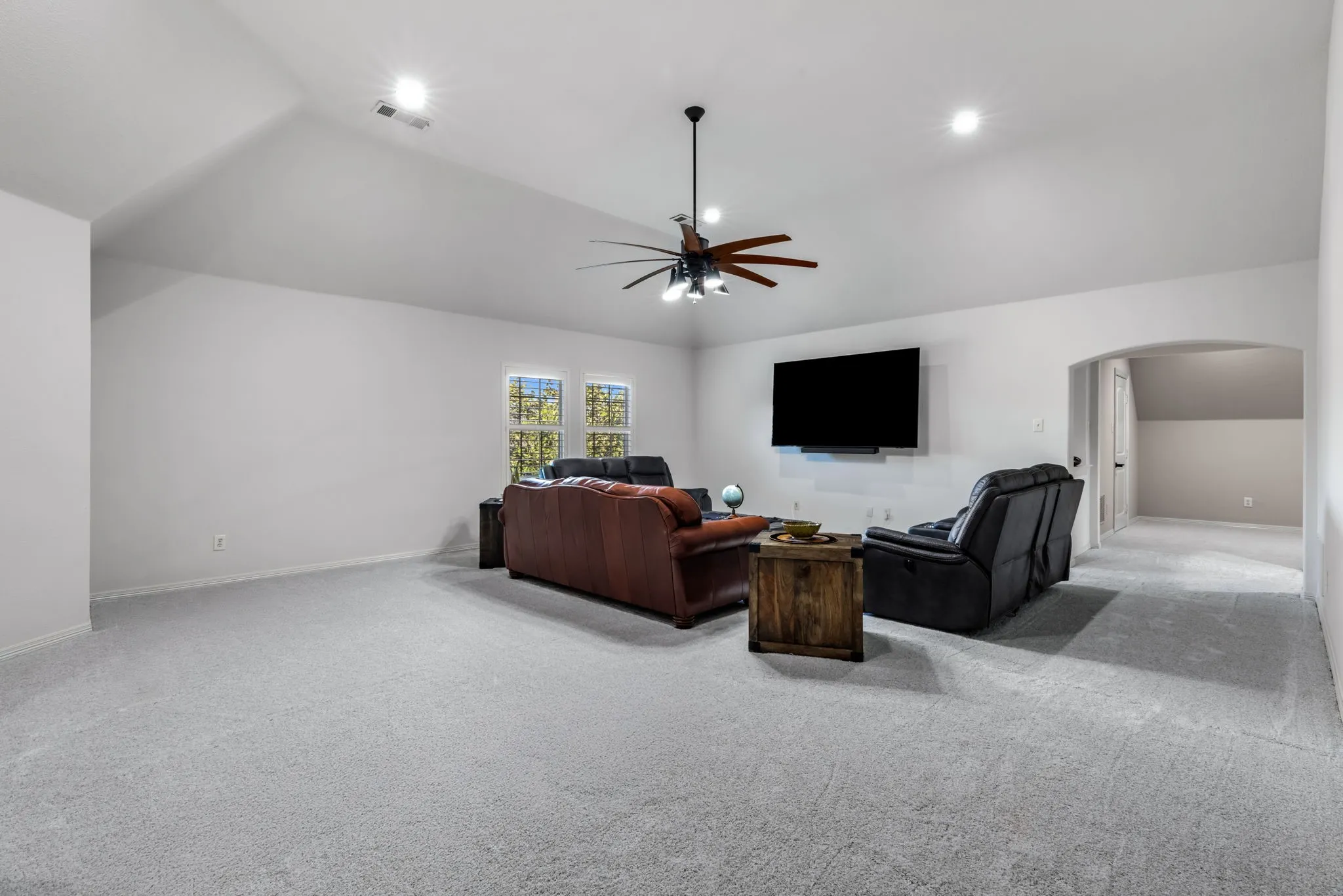 Living area featuring carpet floors, ceiling fan, arched walkways, vaulted ceiling, and recessed lighting