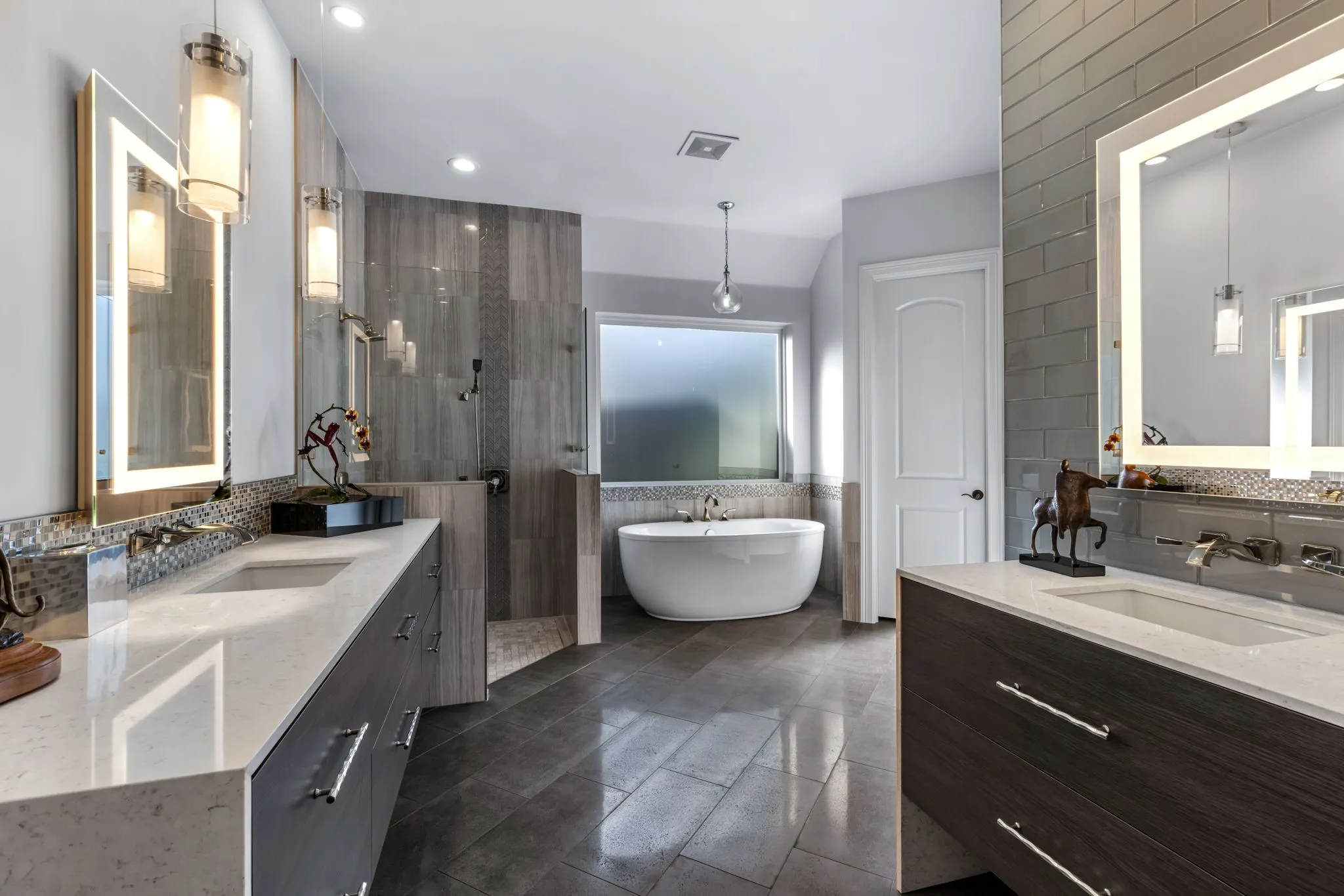 Full bath featuring a freestanding tub, two vanities, tile walls, a walk in shower, and backsplash