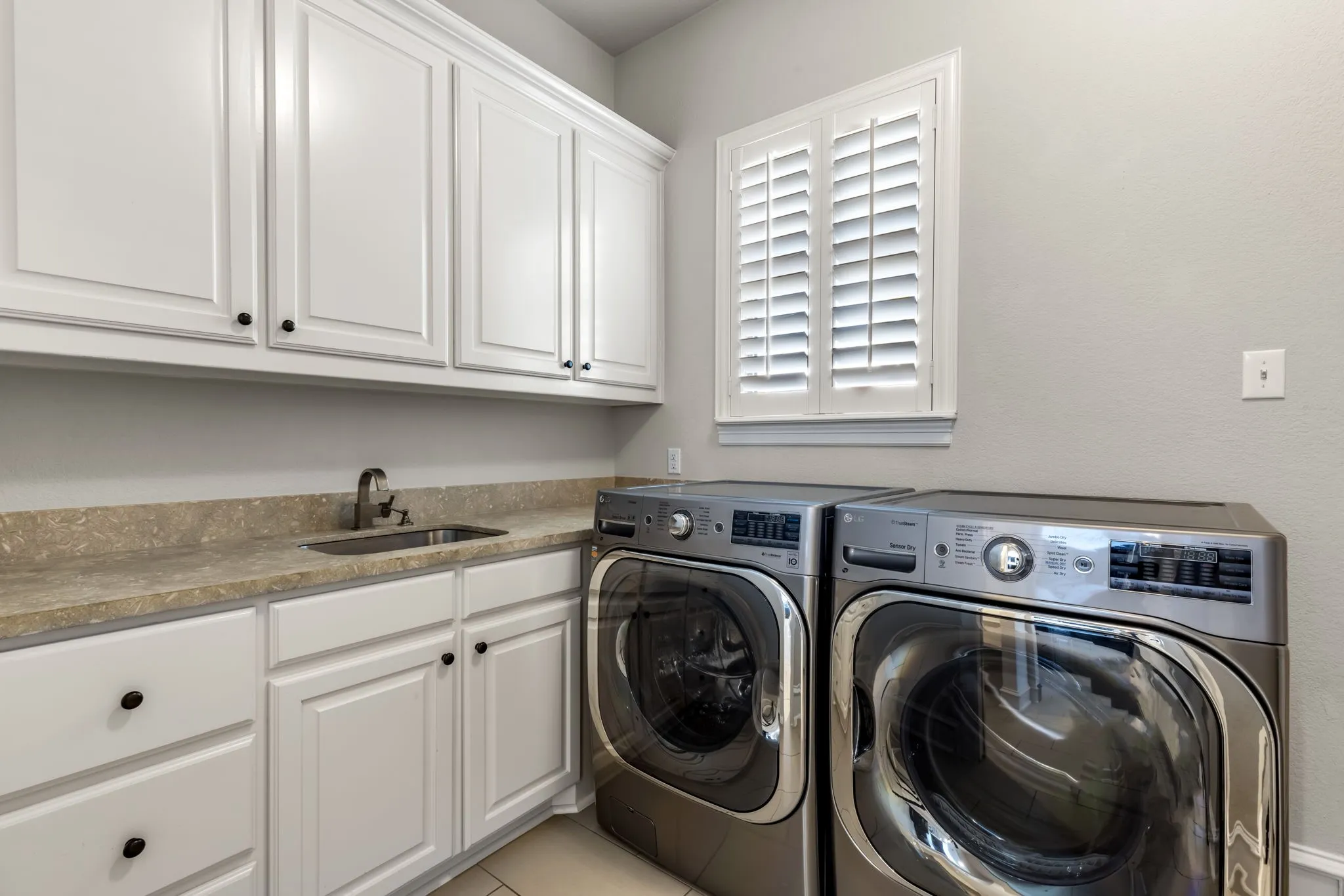 Laundry area featuring separate washer and dryer, cabinet space, and light tile patterned floors