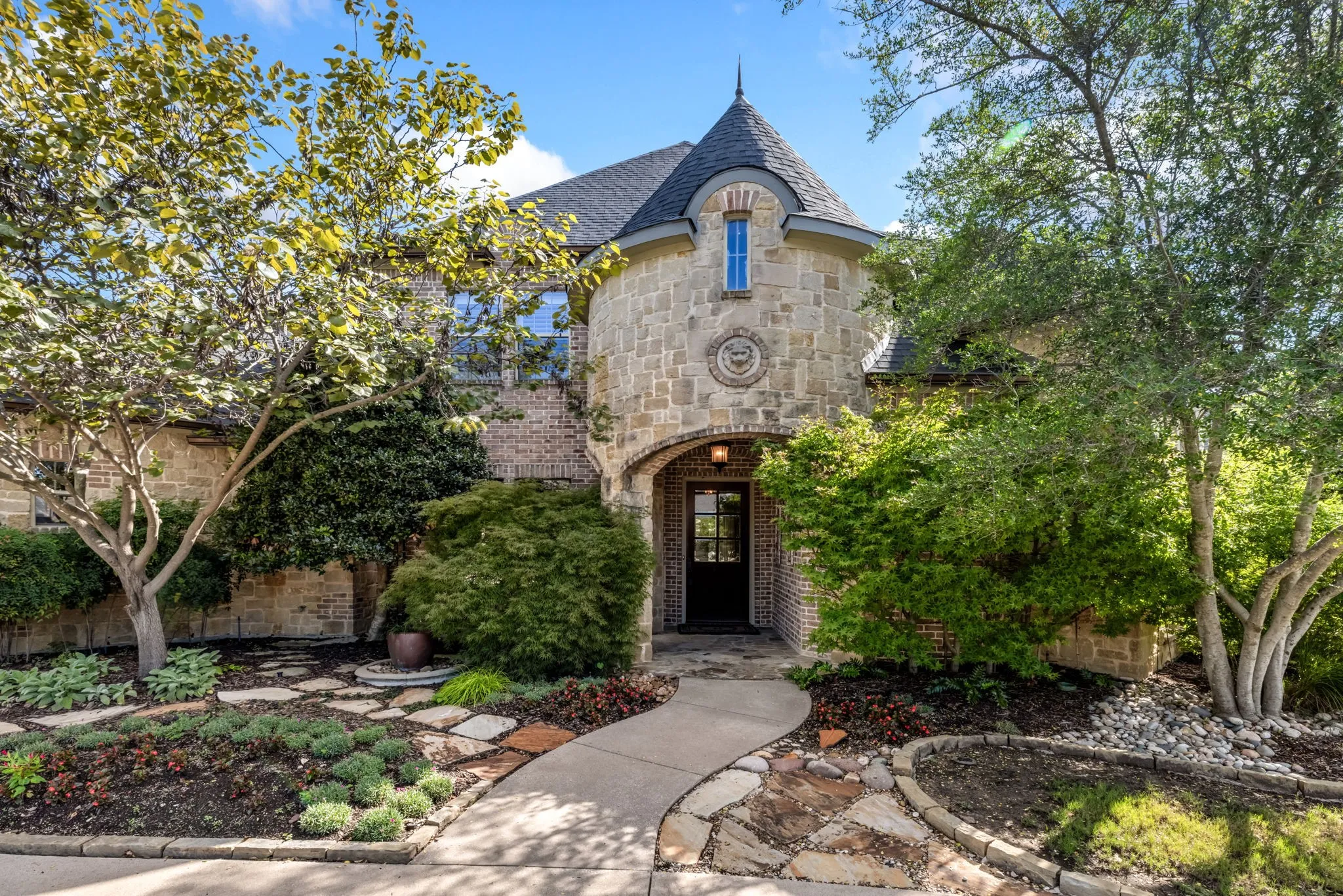 French country inspired facade featuring stone siding, a high end roof, and brick siding