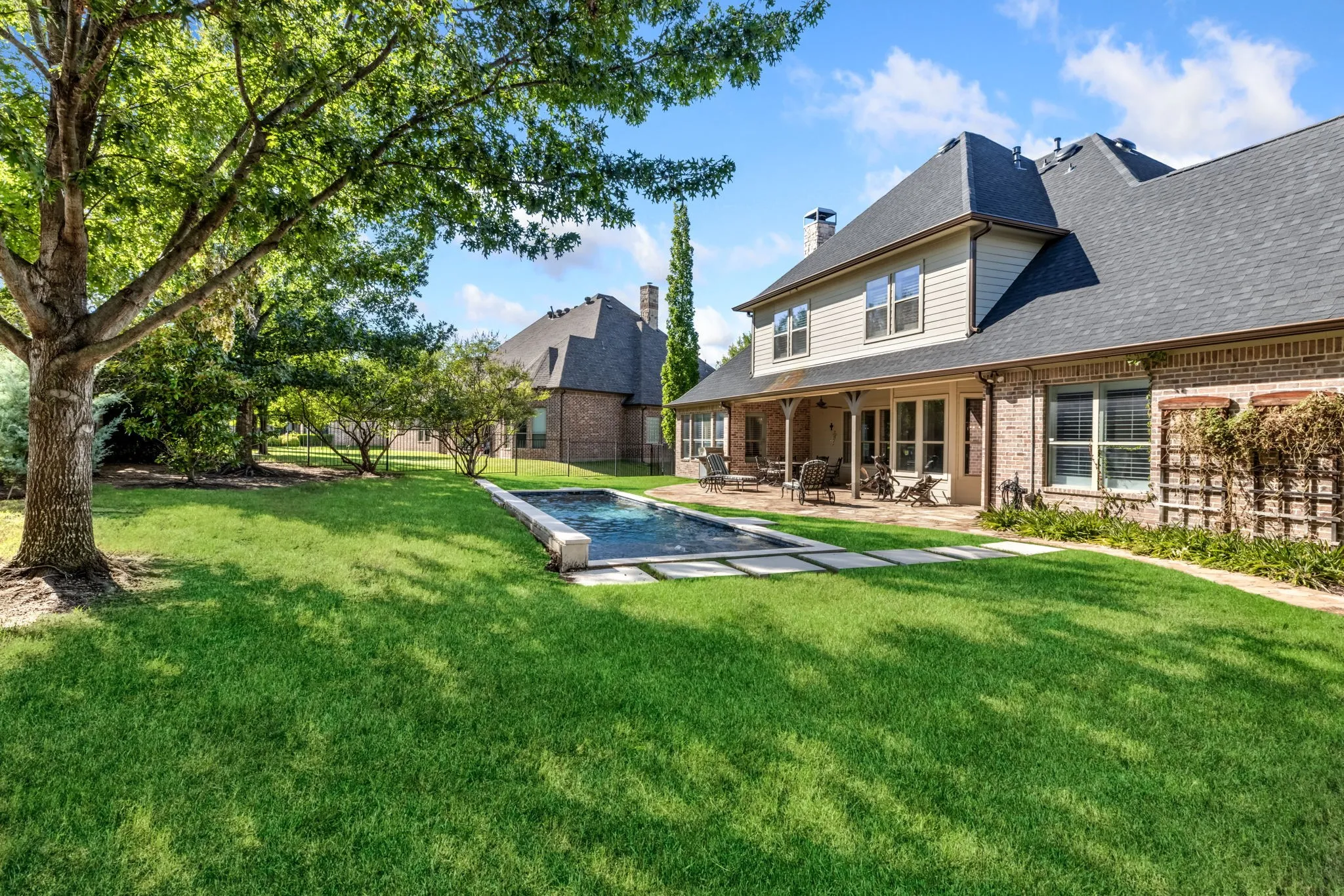 Rear view of property with a patio, a chimney, a fenced backyard, a shingled roof, and brick siding