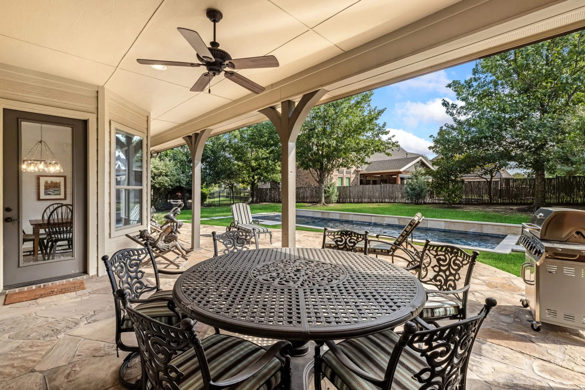Fenced backyard with a patio, ceiling fan, grilling area, and outdoor dining space