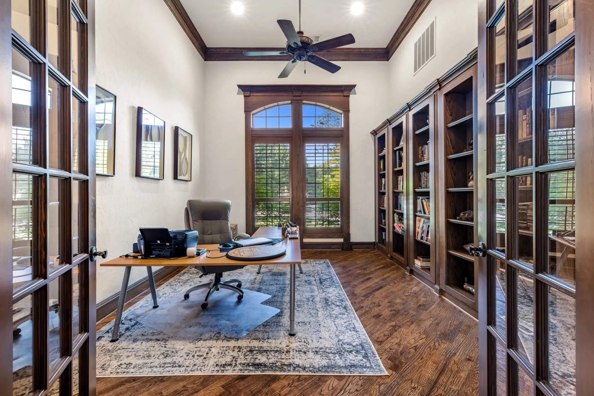 Office area with french doors, ornamental molding, dark wood-style floors, a ceiling fan, and a towering ceiling