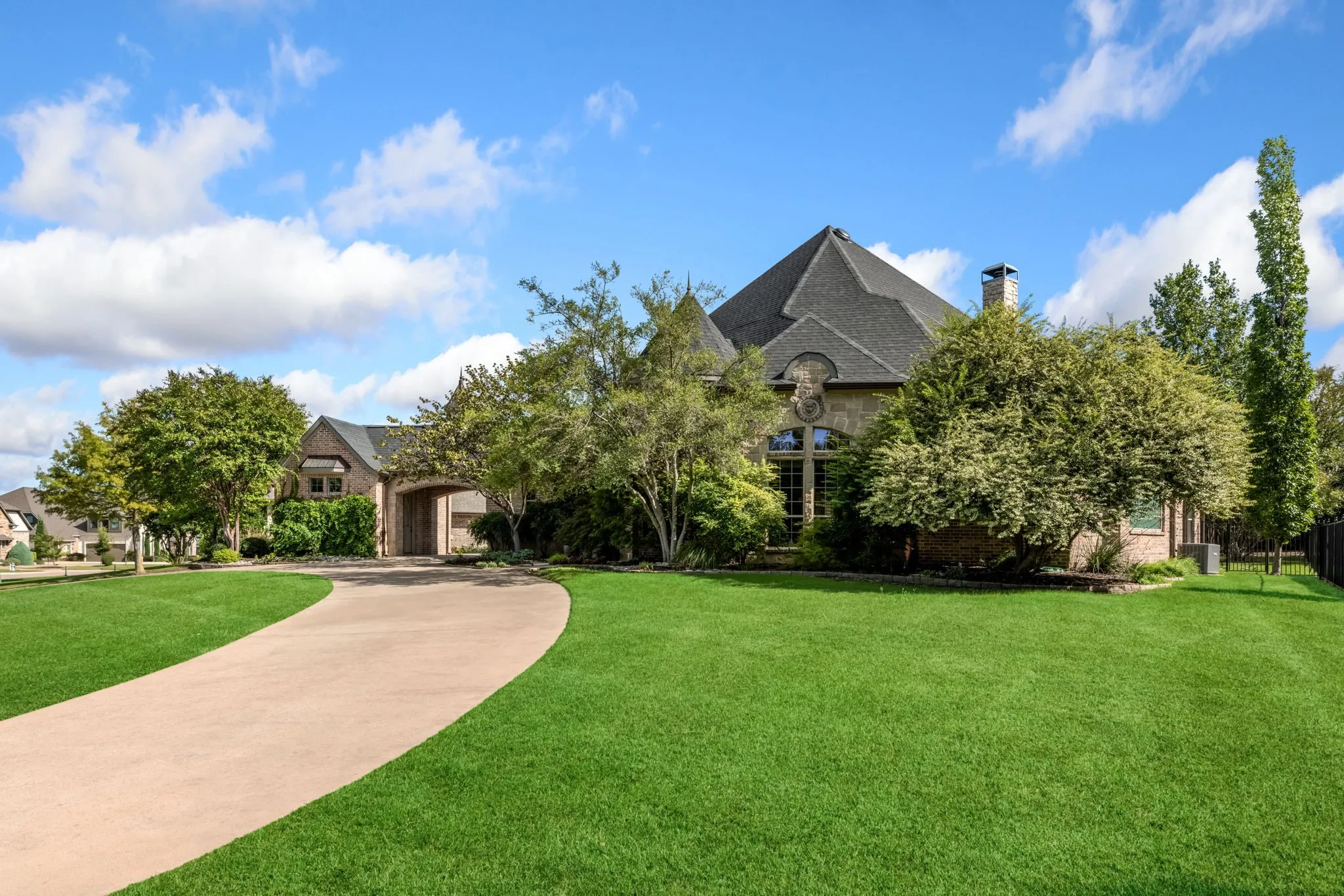 French country inspired facade featuring a front yard, brick siding, a chimney, and curved driveway