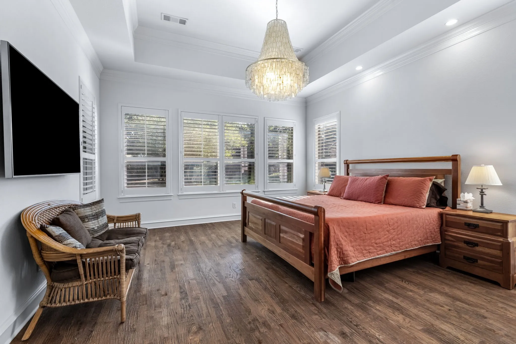 Bedroom with dark wood finished floors, a tray ceiling, ornamental molding, and a​​‌​​​​‌​​‌‌​‌‌​​​‌‌​‌​‌​‌​​​‌​​ chandelier