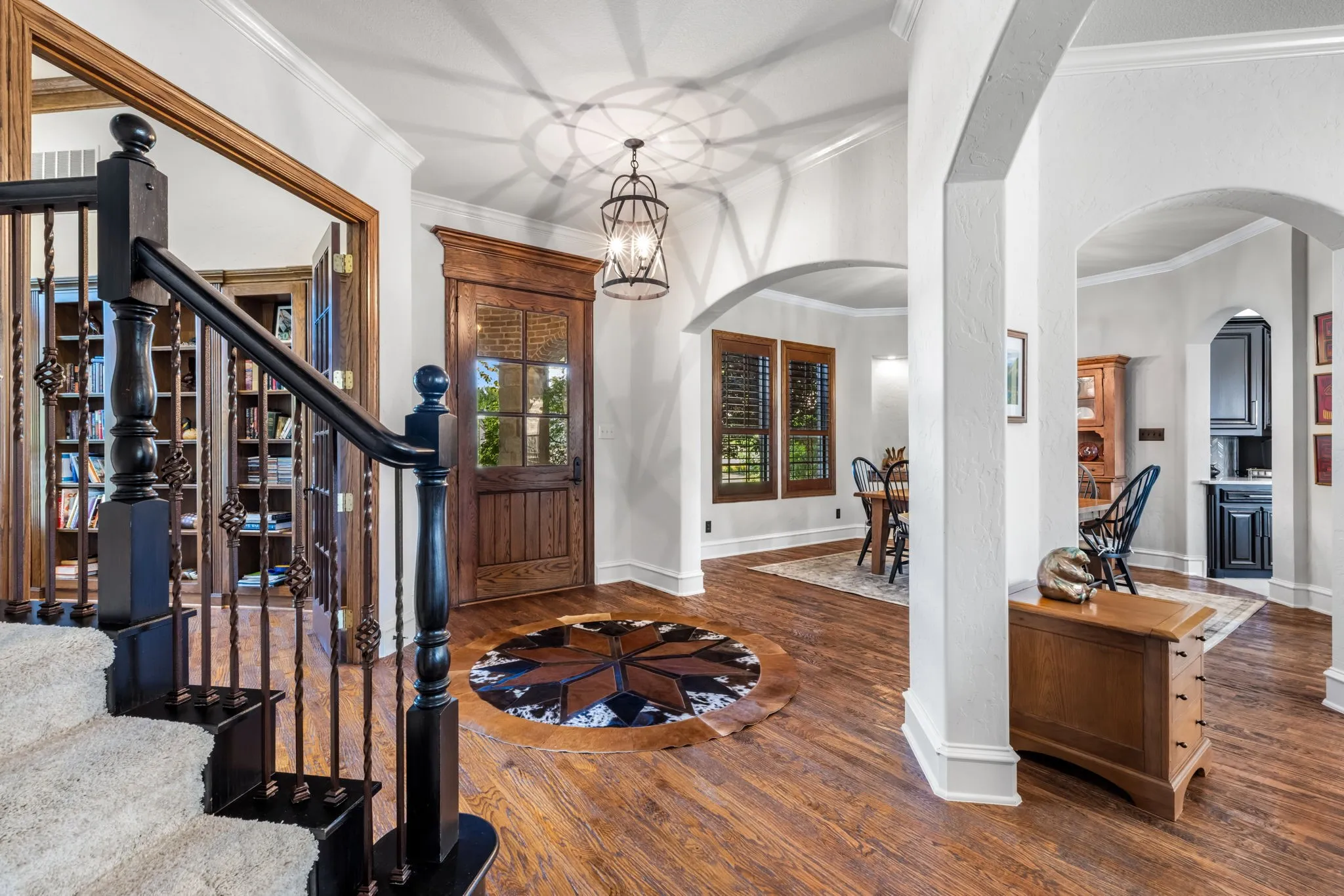 Entryway featuring ornamental molding, wood finished floors, stairs, arched walkways, and a chandelier