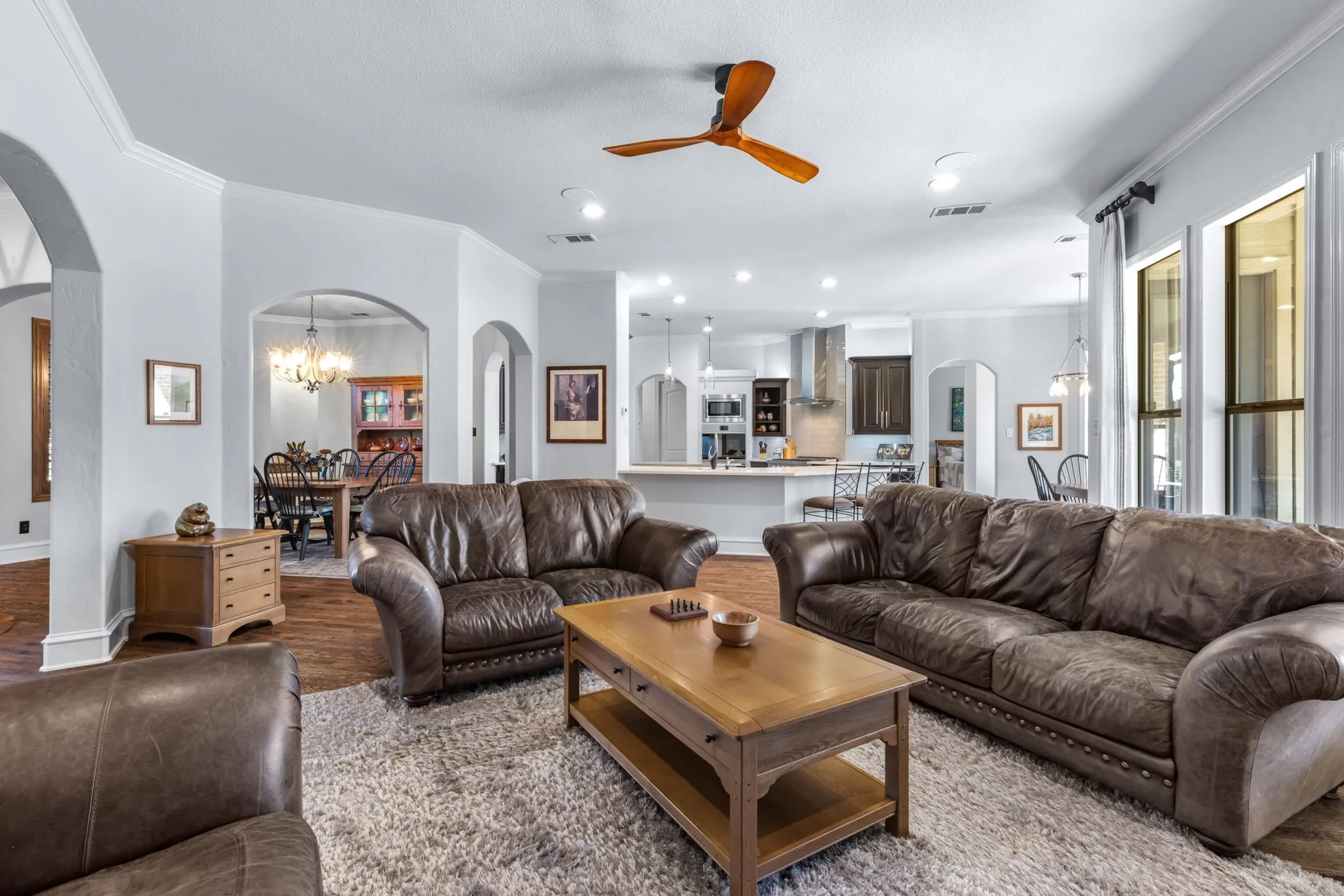 Living room with crown molding, arched walkways, a chandelier, recessed lighting, and ceiling fan
