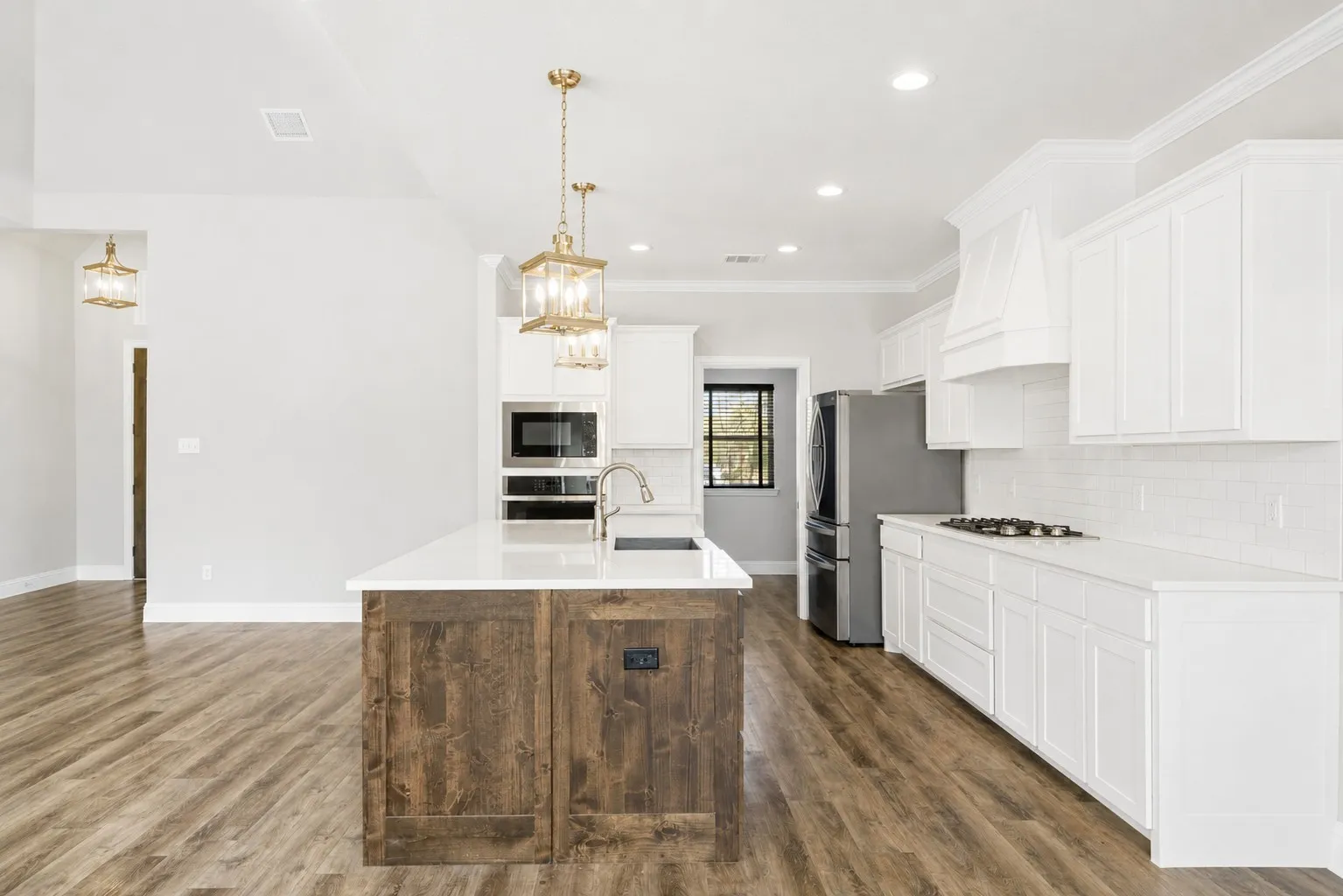 Crisp white cabinetry, a classic subway tile backsplash, and sleek quartz countertops create a clean, timeless look, while the contrasting wood-accented island adds character and warmth.