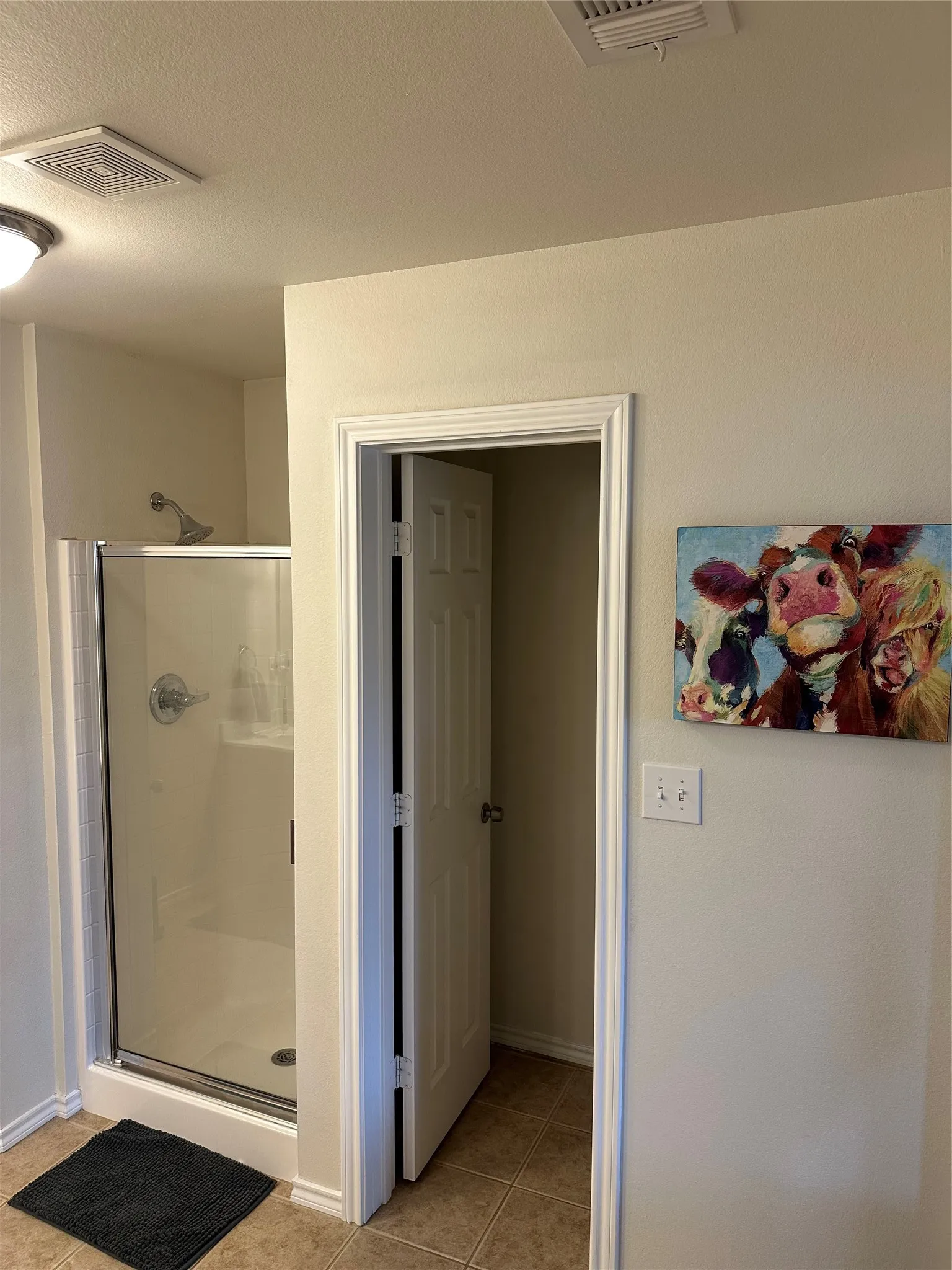 Full bathroom featuring a shower stall, light tile patterned flooring, and a textured ceiling