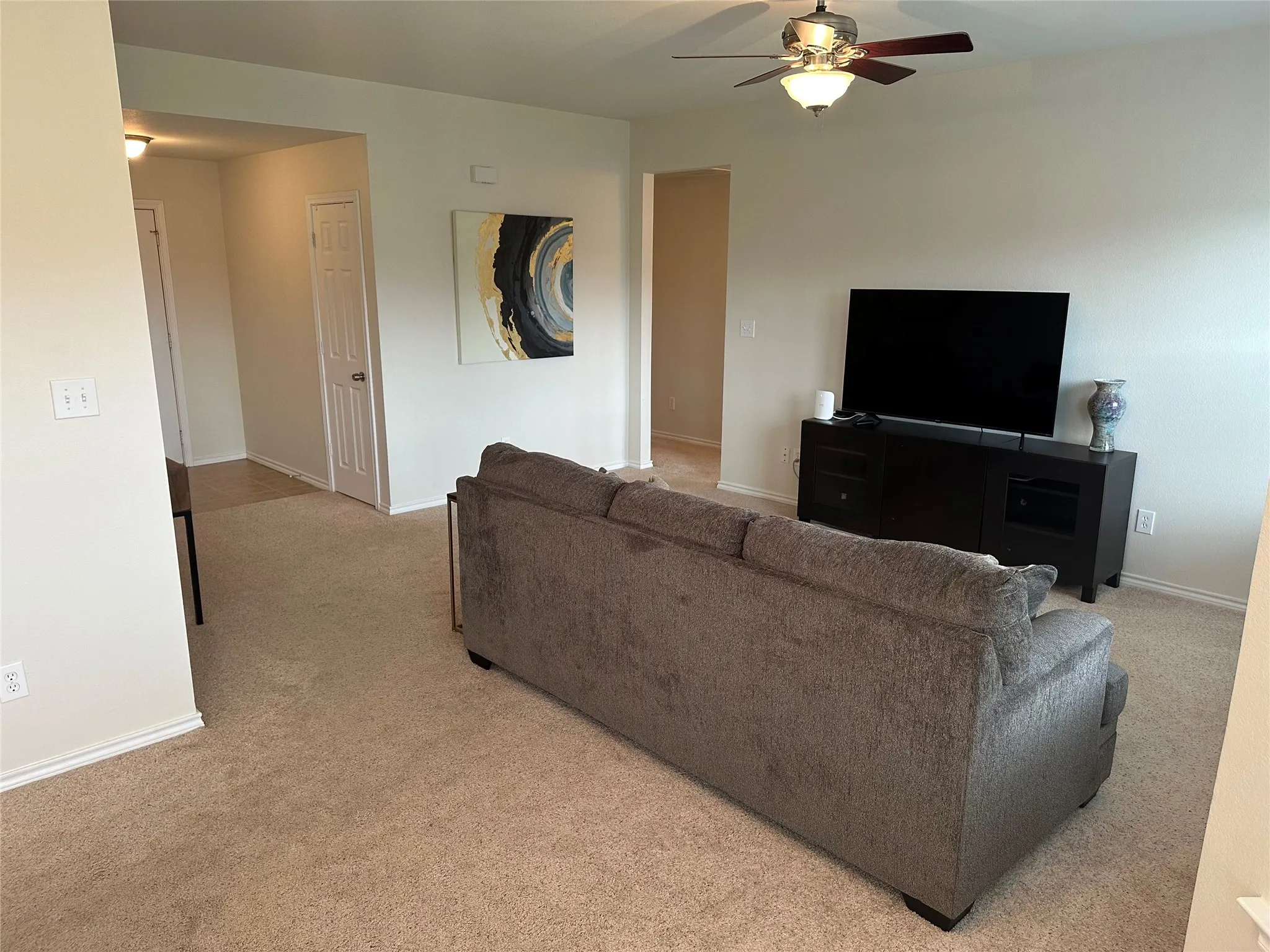 Living area with ceiling fan and light carpet