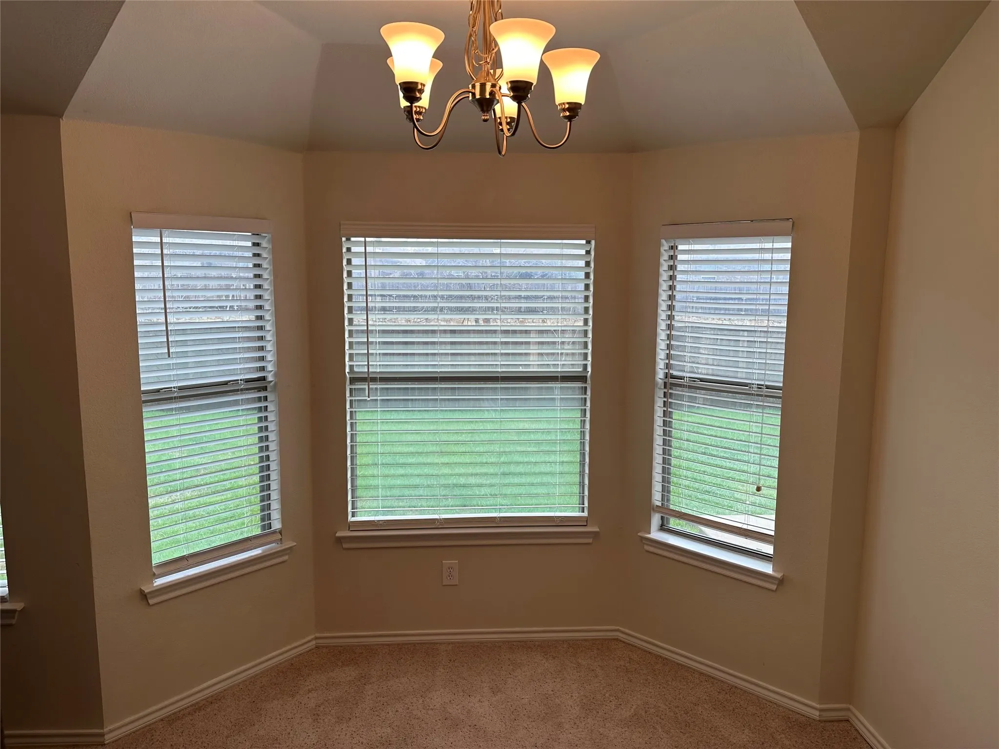 Unfurnished dining area featuring suspended lighting, carpet floors, plenty of natural light, and lofted ceiling