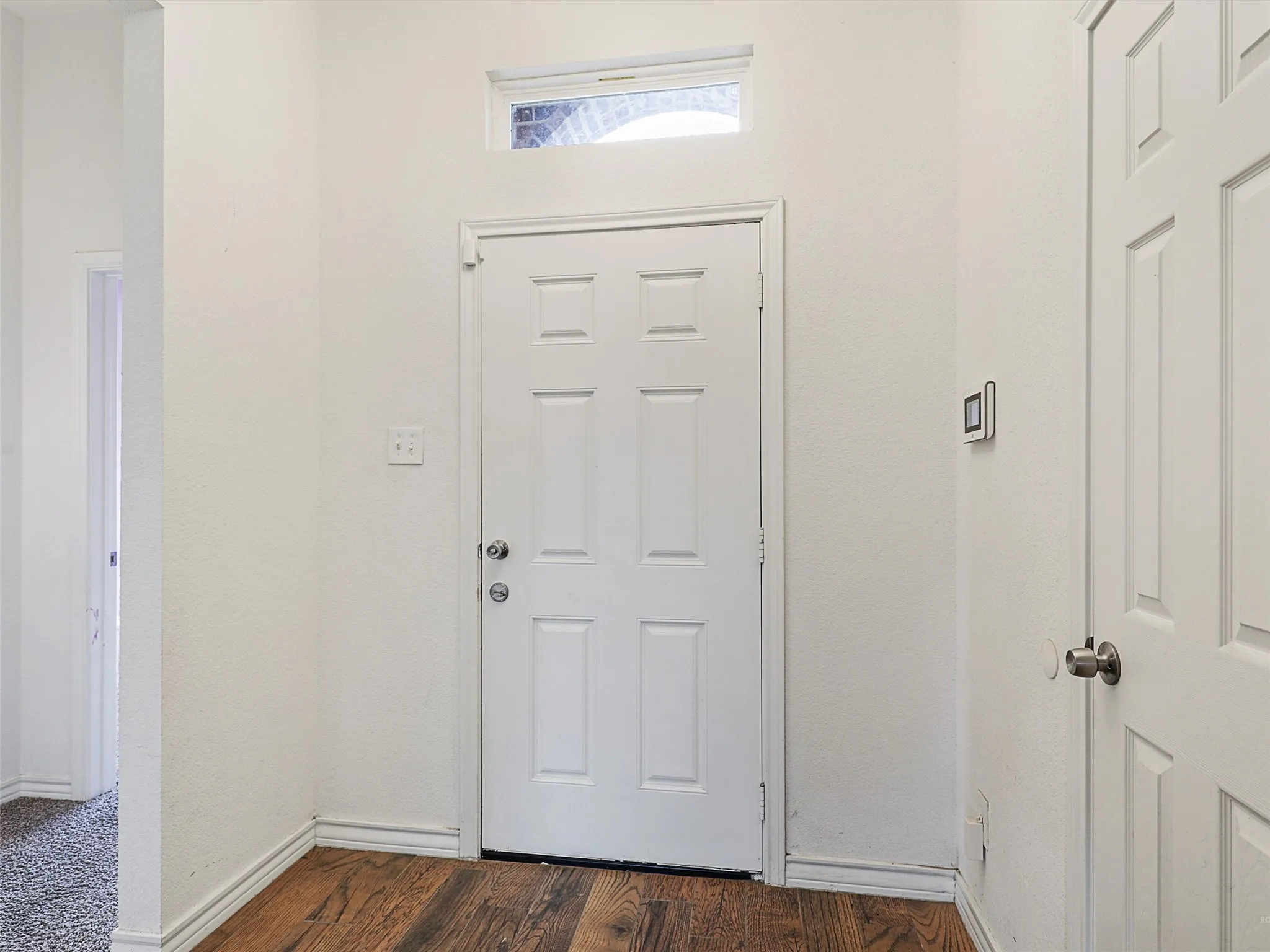 Foyer with dark wood-type flooring and baseboards