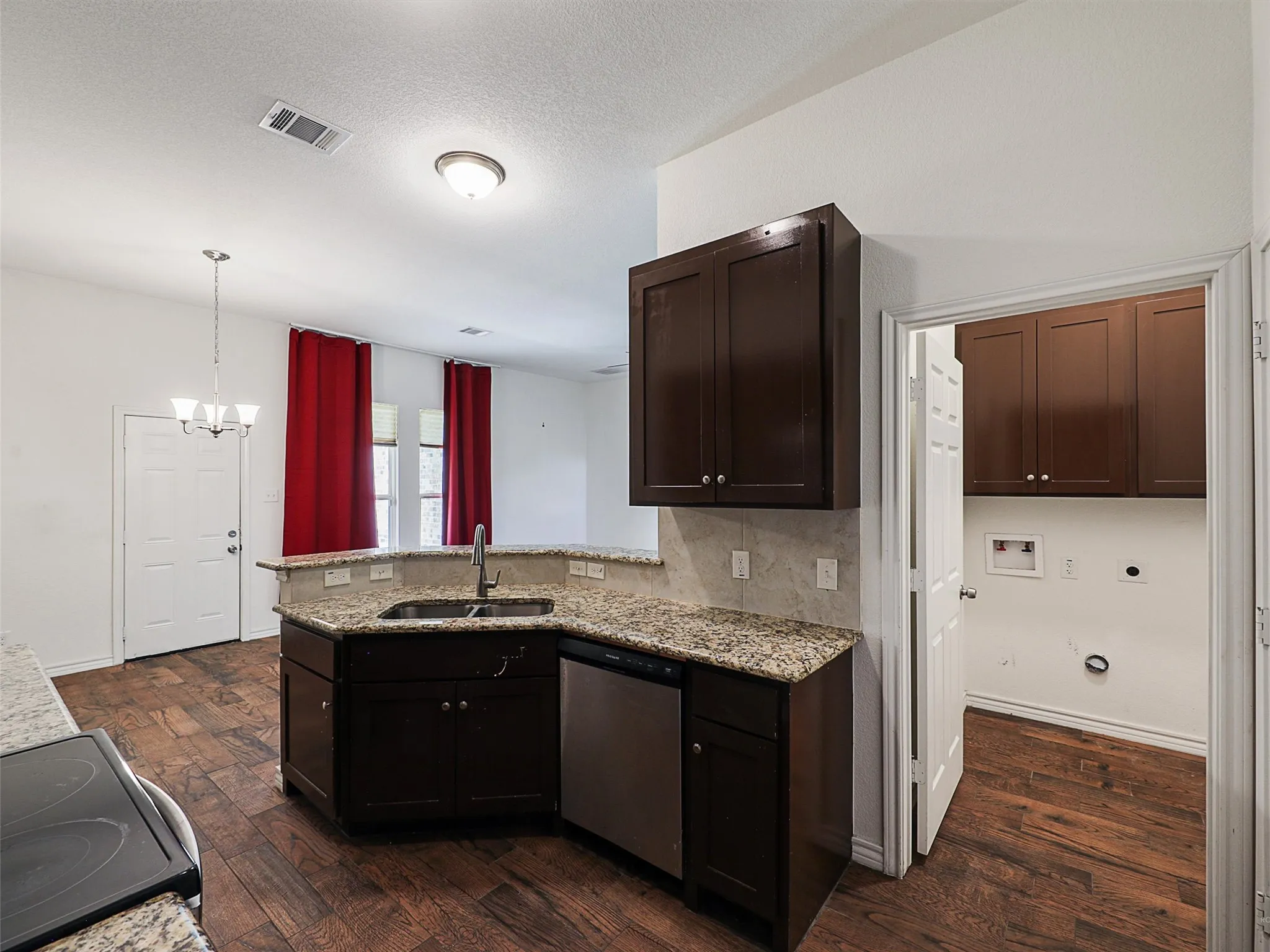 Kitchen featuring a peninsula, black electric range, light stone countertops, suspended lighting, and stainless steel dishwasher