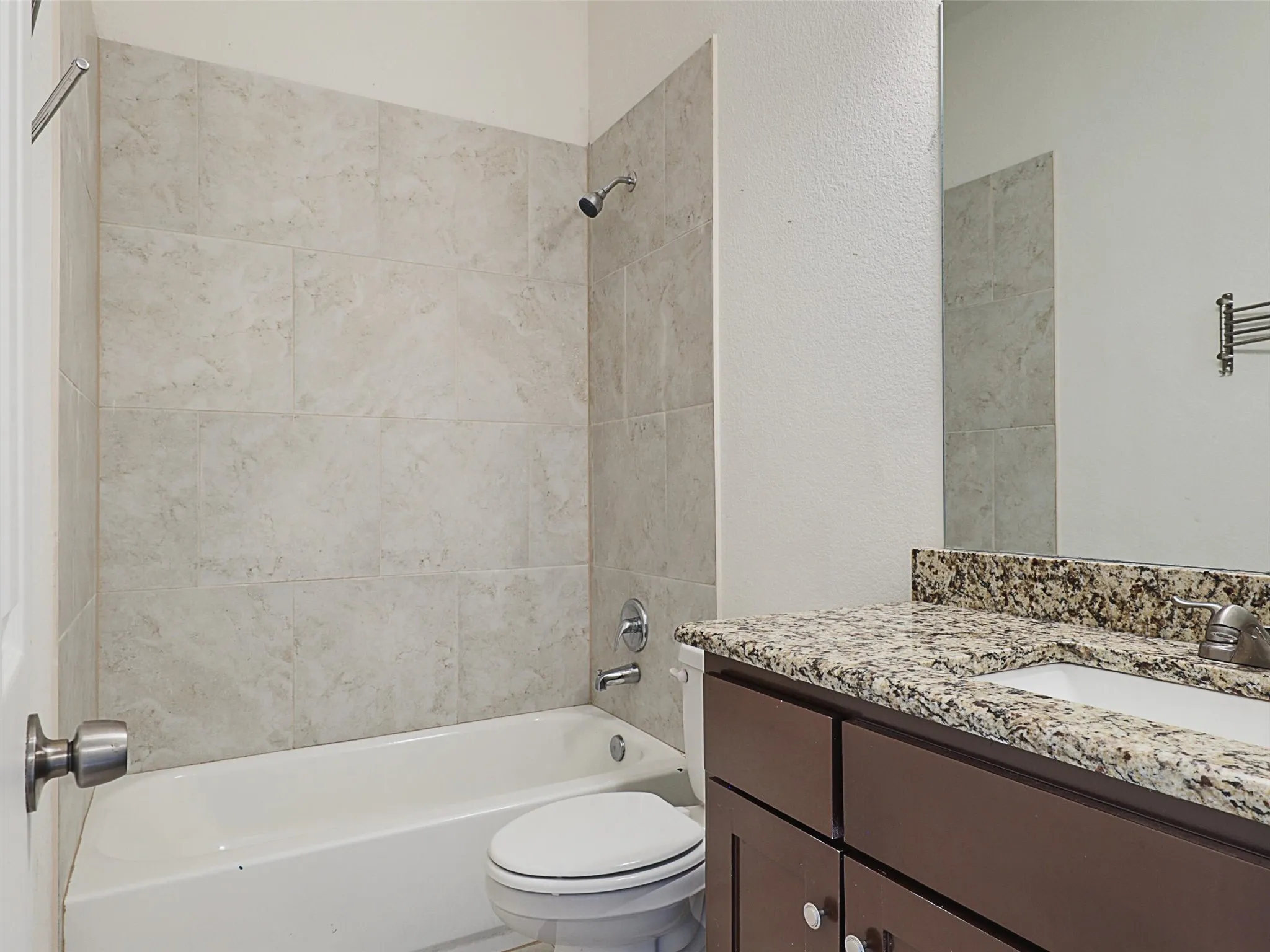 Full bath featuring vanity, shower / tub combination, and a textured wall