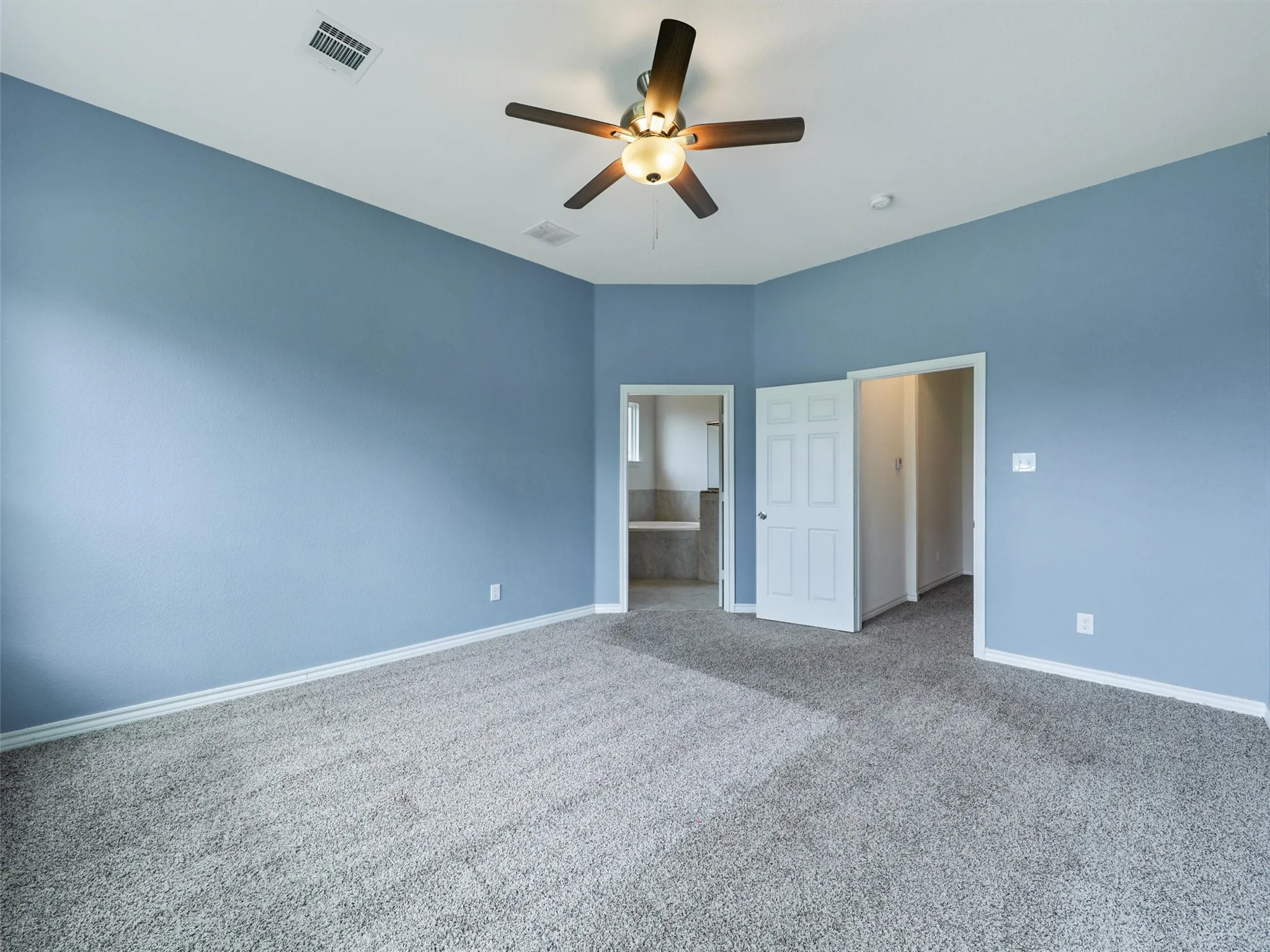 Unfurnished bedroom featuring carpet floors, ensuite bathroom, and ceiling fan