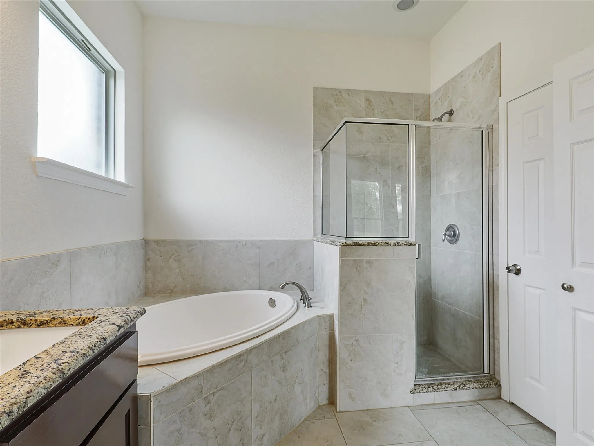 Full bath featuring vanity, a stall shower, a garden tub, and light tile patterned floors