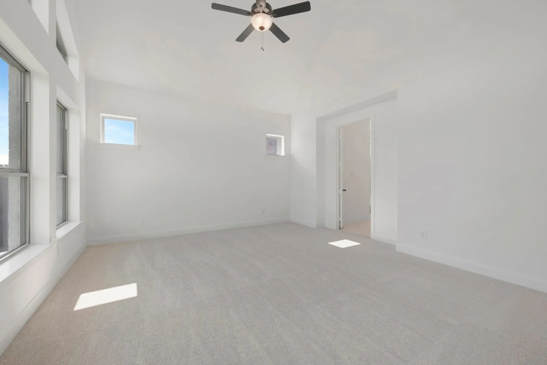 Bright room featuring an angled ceiling, light-toned carpeting, and multiple windows