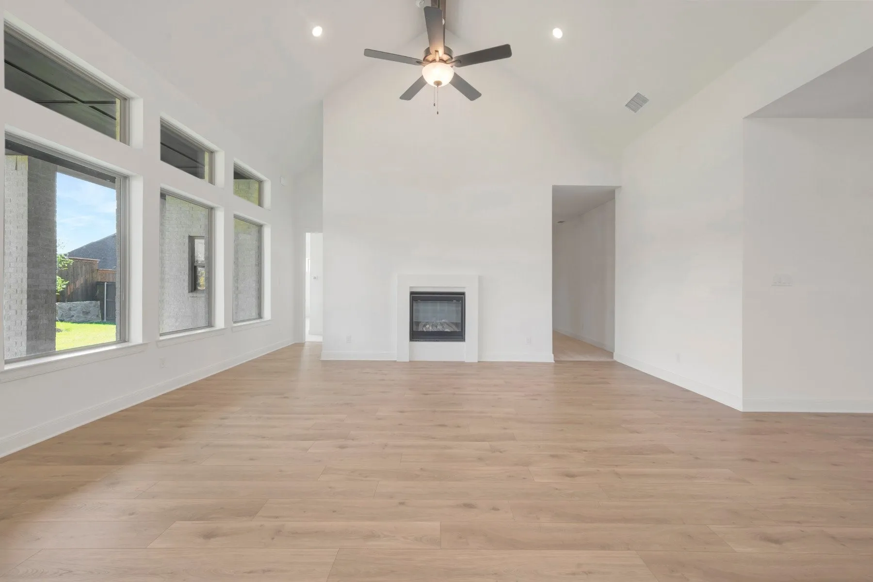 Open concept living space featuring a vaulted ceiling, recessed lighting, and a contemporary fireplace