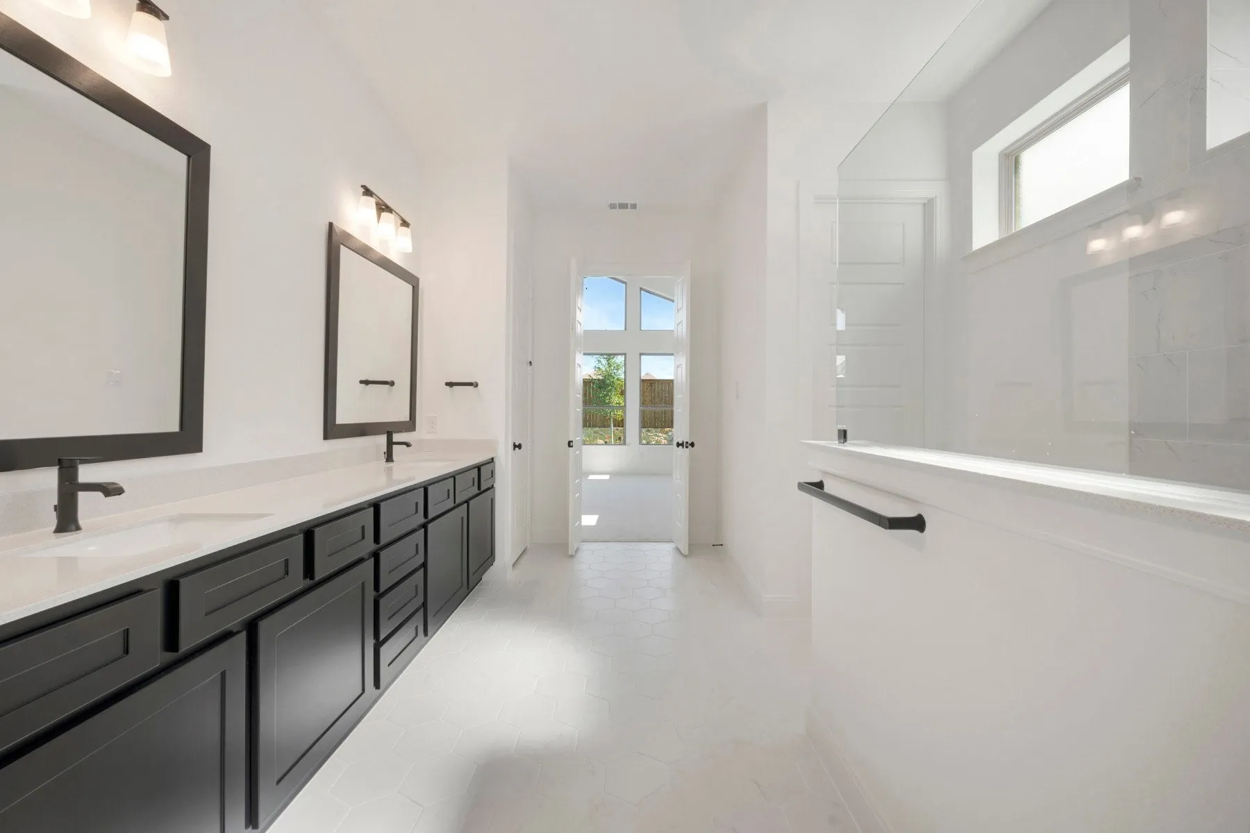 Spacious bathroom featuring a dual vanity with dark cabinetry and light-toned countertops, contemporary square mirrors, and matte black hardware