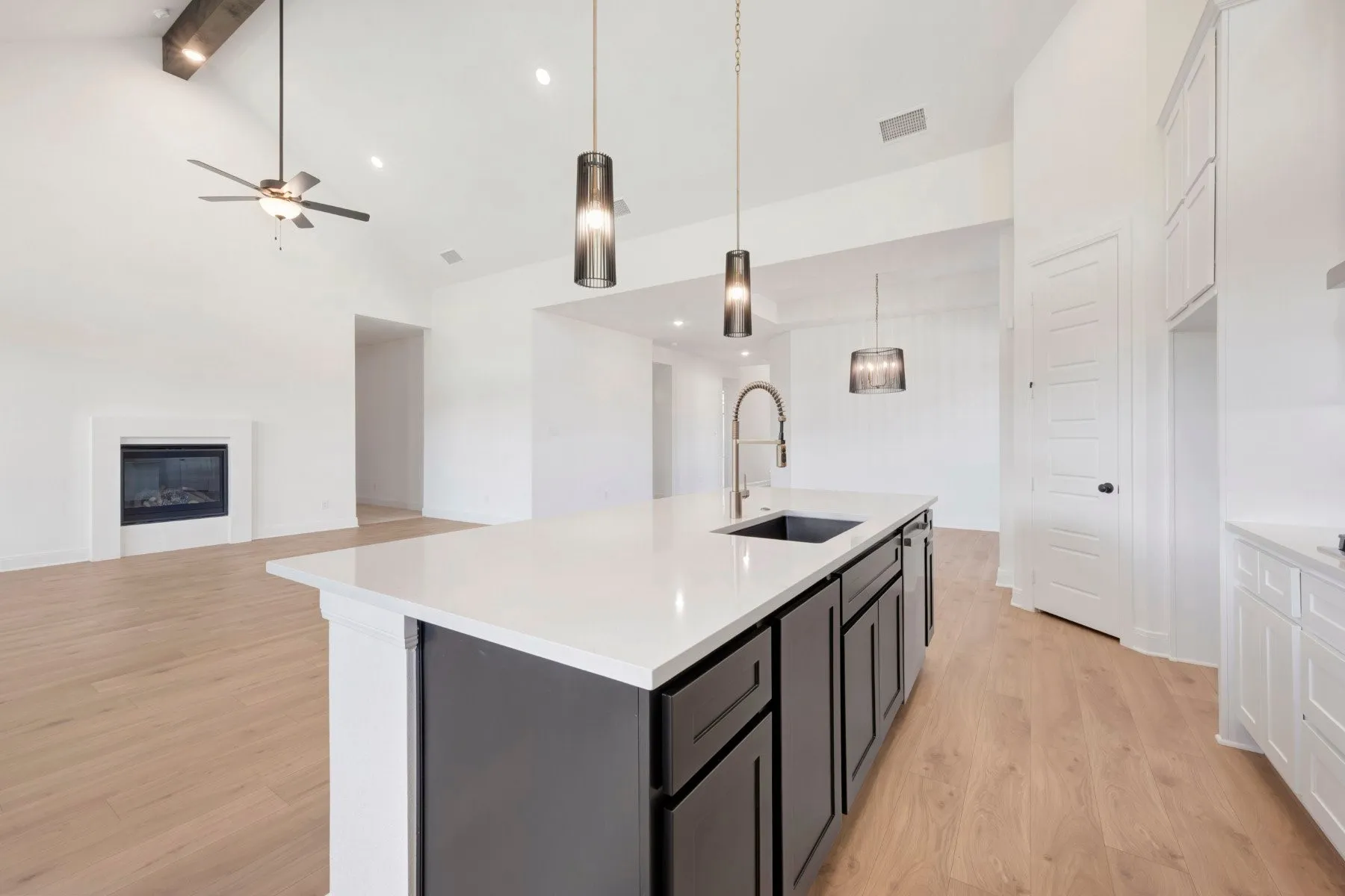 Kitchen island featuring a white countertop, dark cabinetry, and an integrated sink with a gooseneck faucet