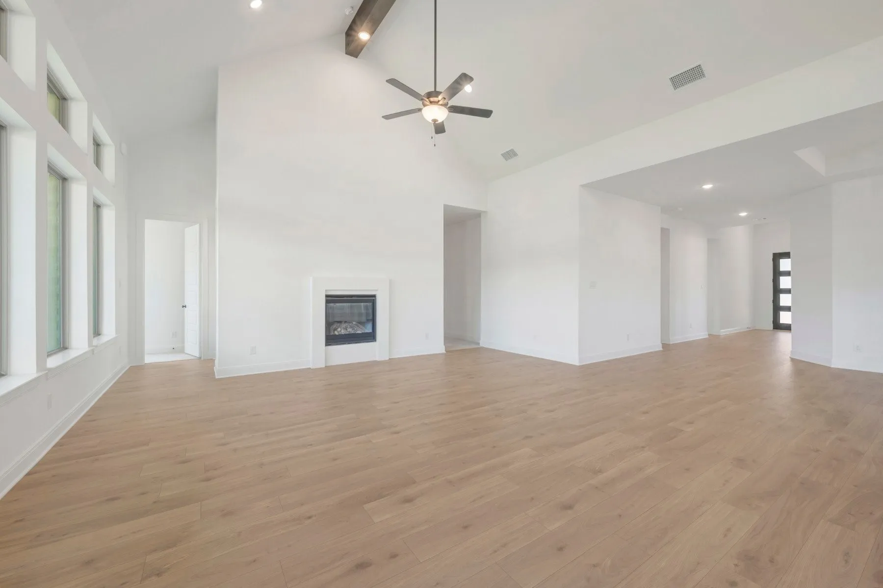 Spacious living area featuring high vaulted ceilings with exposed wood-finish beams, a ceiling fan, and recessed lighting