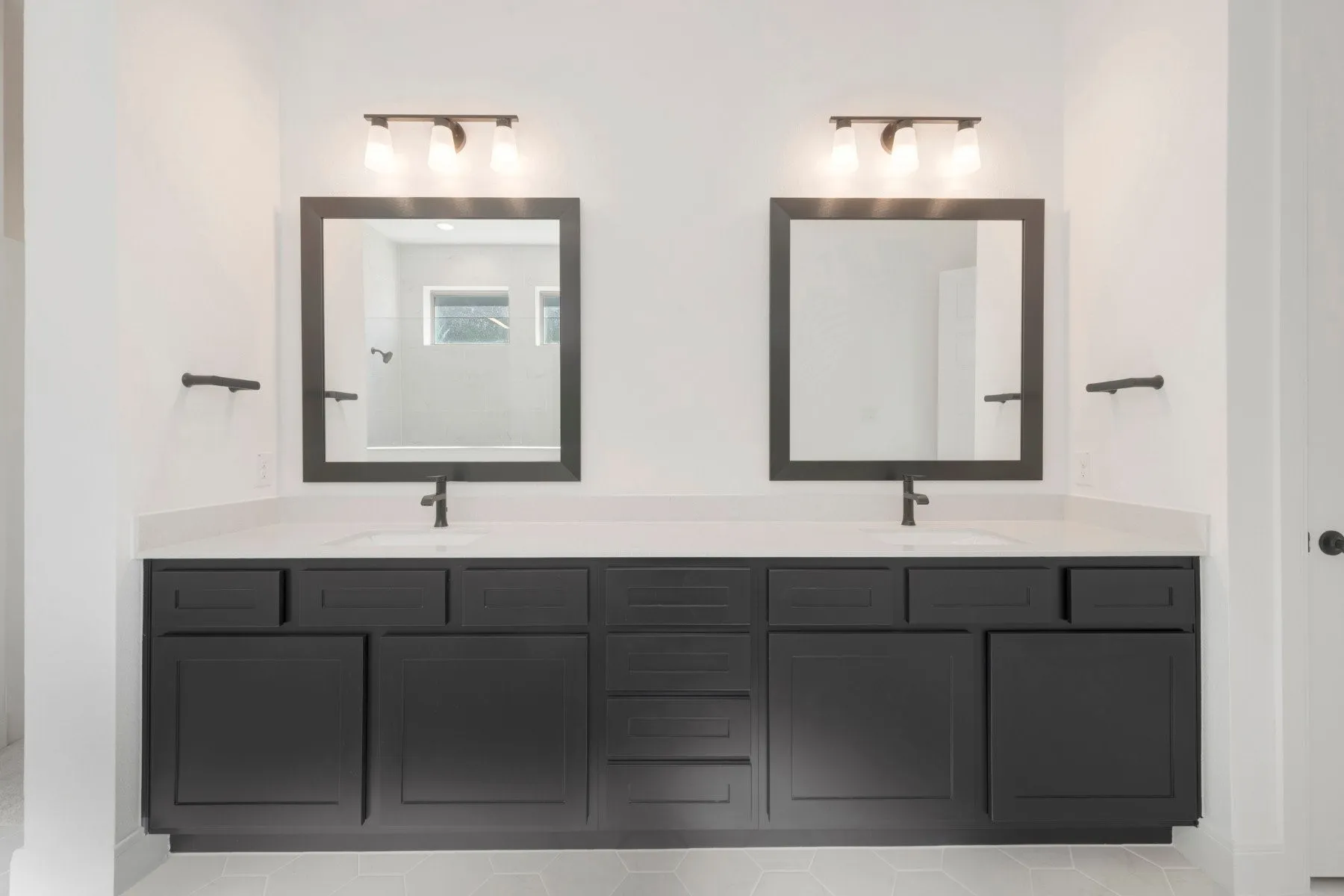 Dual vanity featuring dark cabinetry, white countertops, rectangular undermount sinks, and matte black fixtures