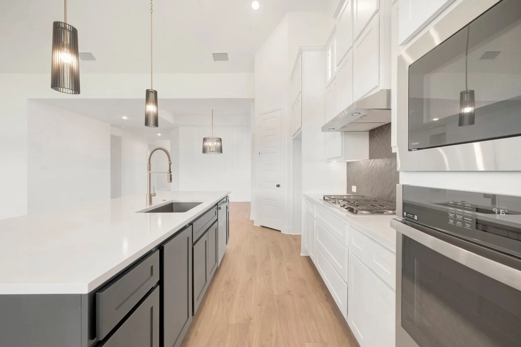 Modern kitchen featuring an extended island with a built-in sink and faucet, complemented by two-tone cabinetry