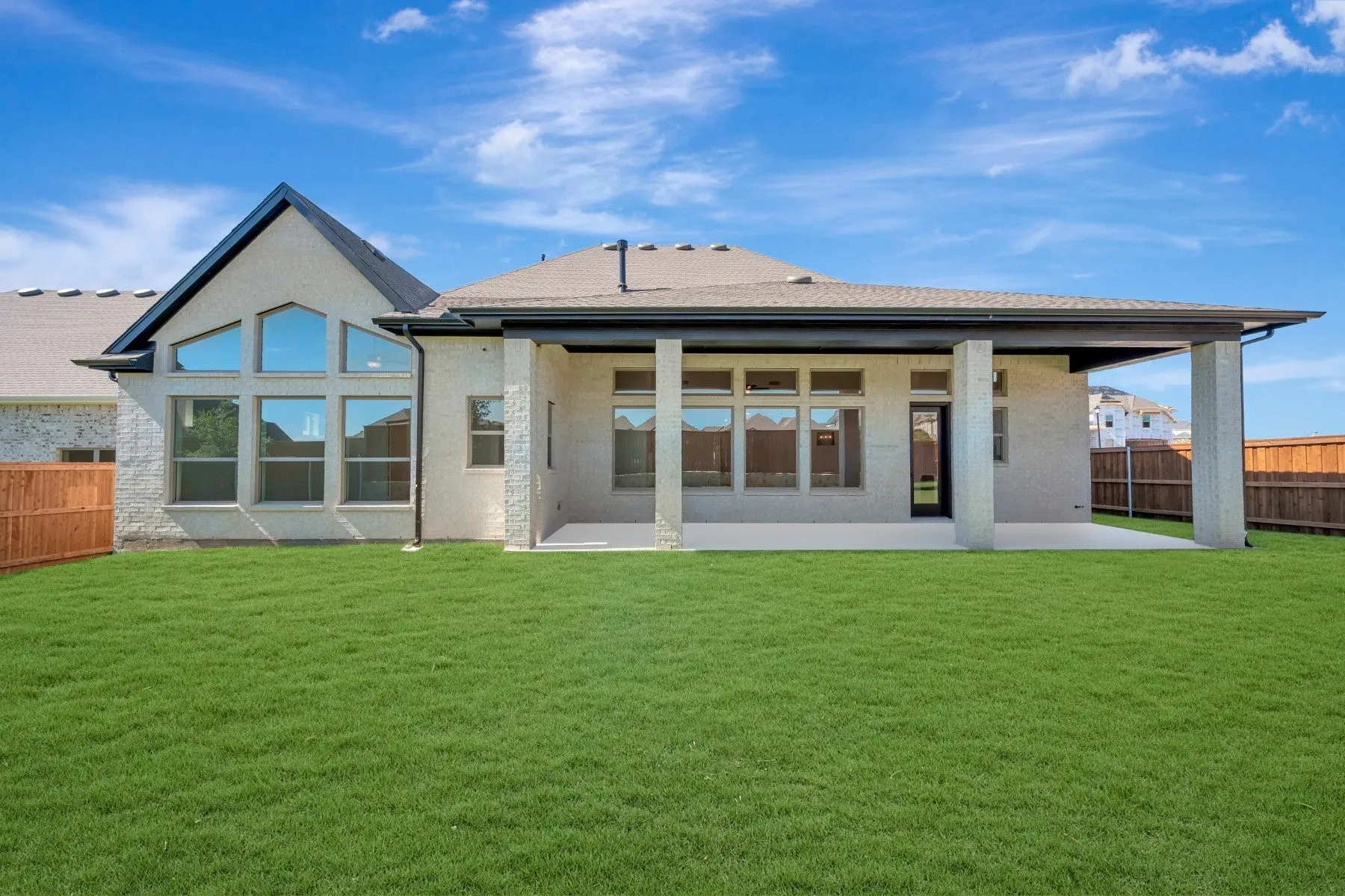 Expansive backyard featuring a manicured lawn, a covered patio, and a privacy fence