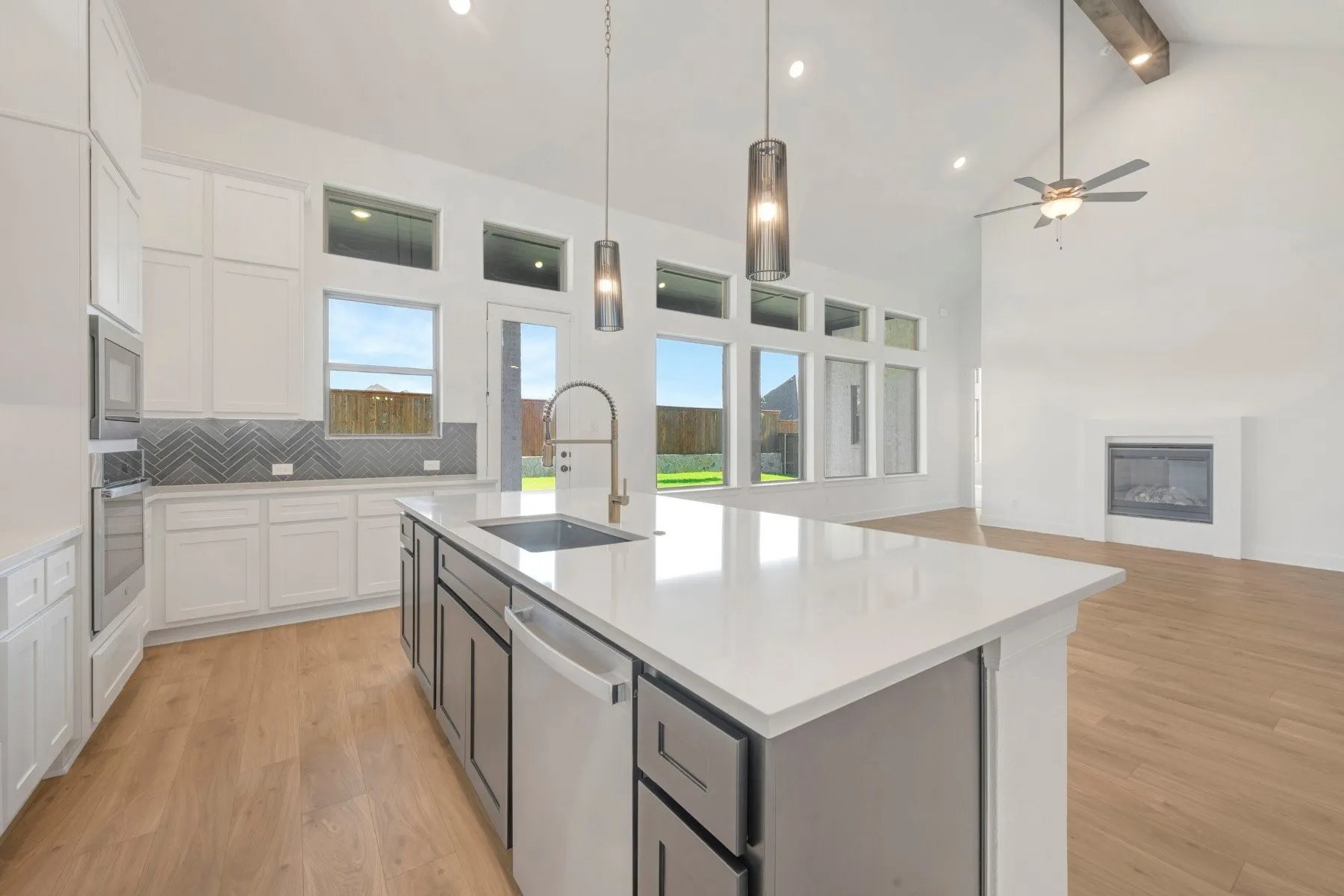 Open-concept living area featuring a kitchen island with a quartz countertop, stainless steel sink, and pendant lighting