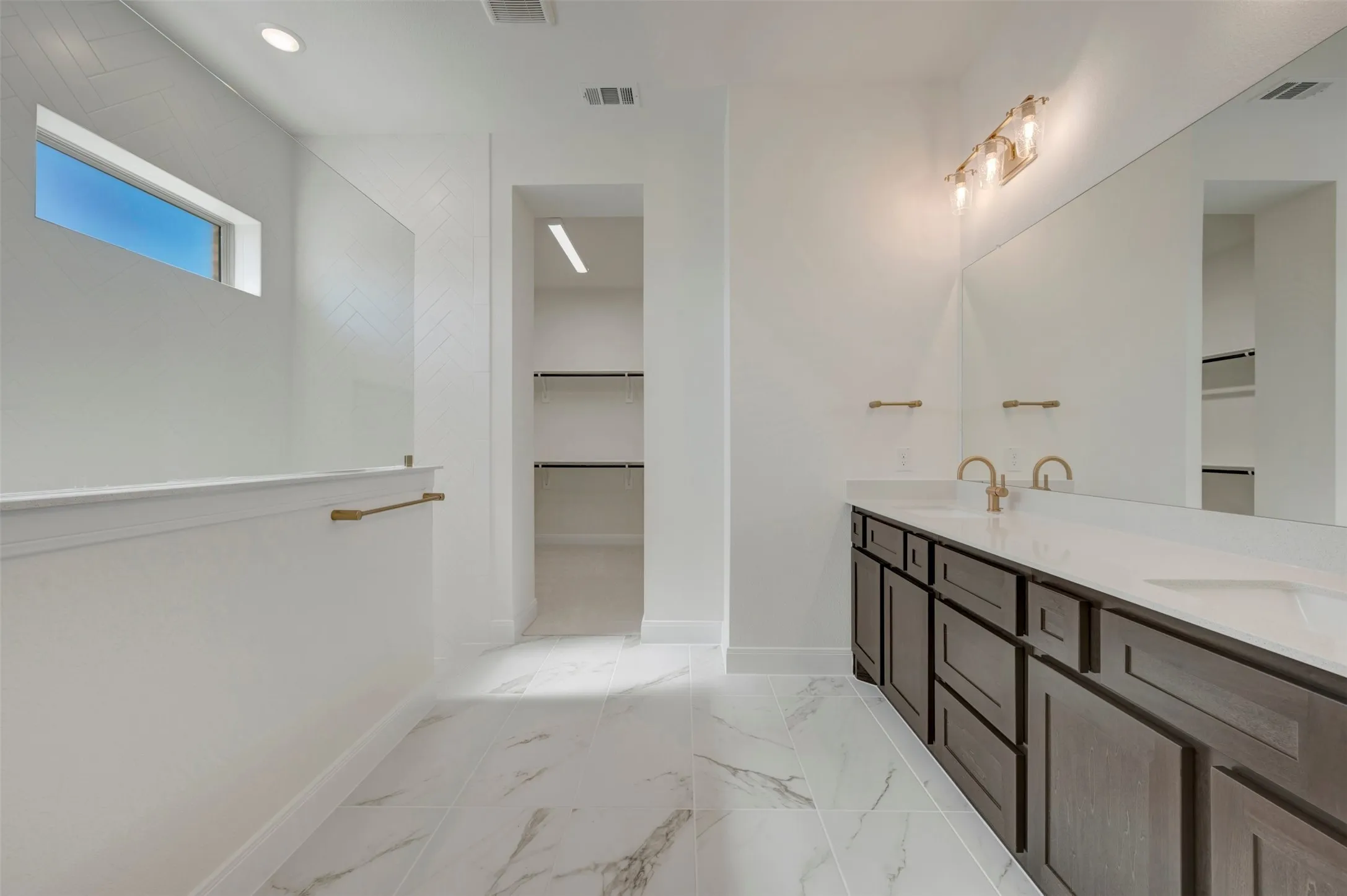 Bathroom featuring a dual vanity with dark wood cabinetry, white countertops, and gold-toned fixtures