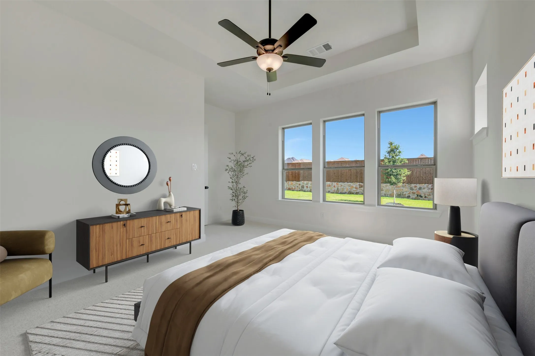 Spacious interior featuring a tray ceiling, ceiling fan with integrated lighting, and three large windows