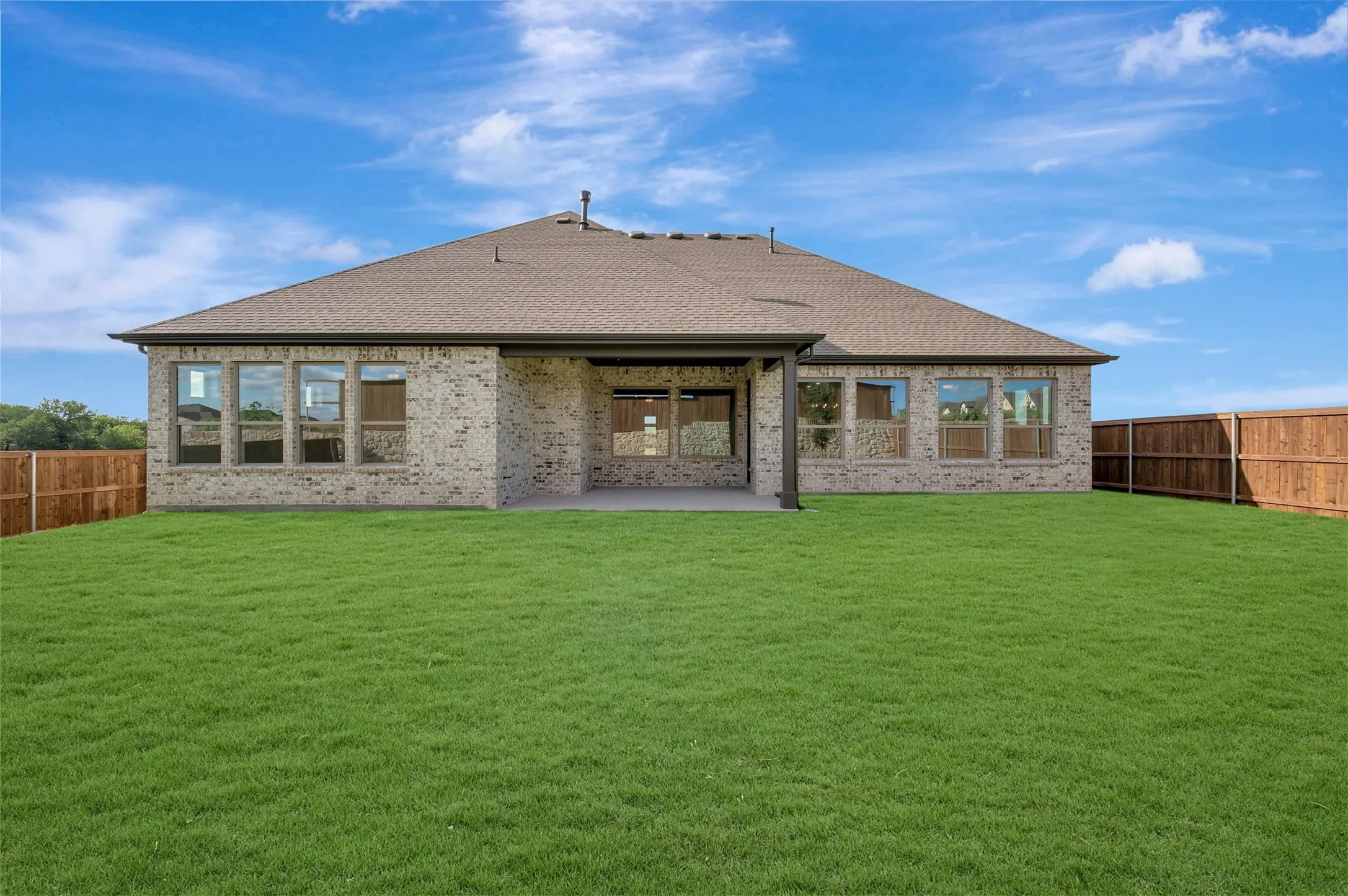 Expansive rear yard featuring green lawn, a covered patio, and privacy fencing