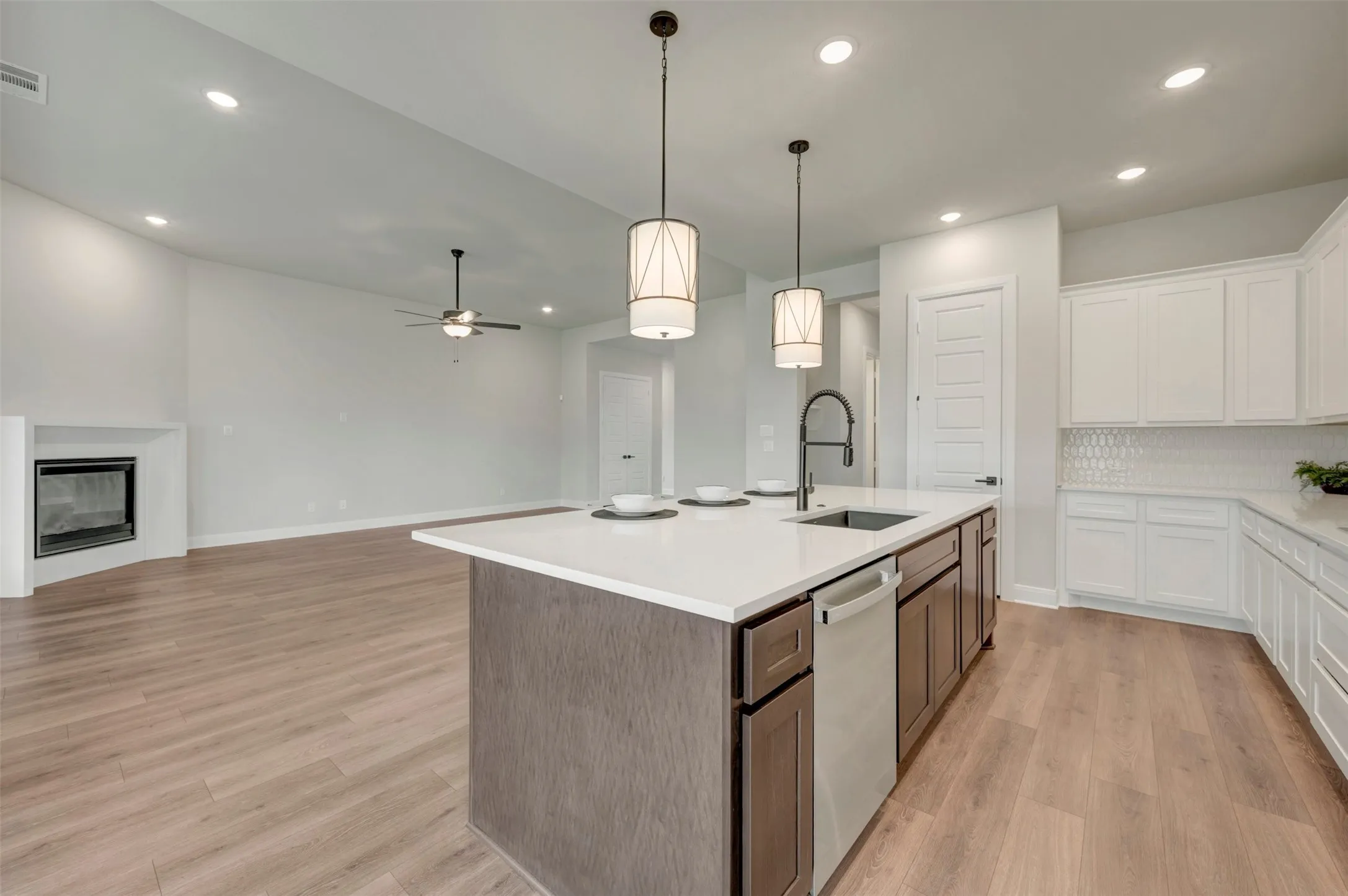 Kitchen island featuring a white countertop, undermount sink with a matte black faucet, and pendant lighting