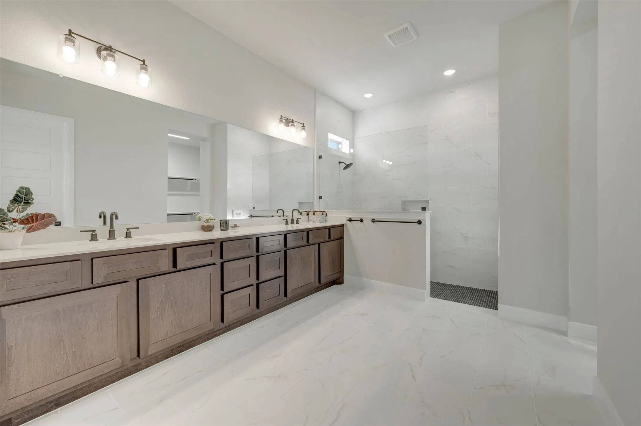 Expansive bathroom featuring a dual vanity with wood-finish cabinetry, light-toned countertops, and dual wall-mounted mirrors