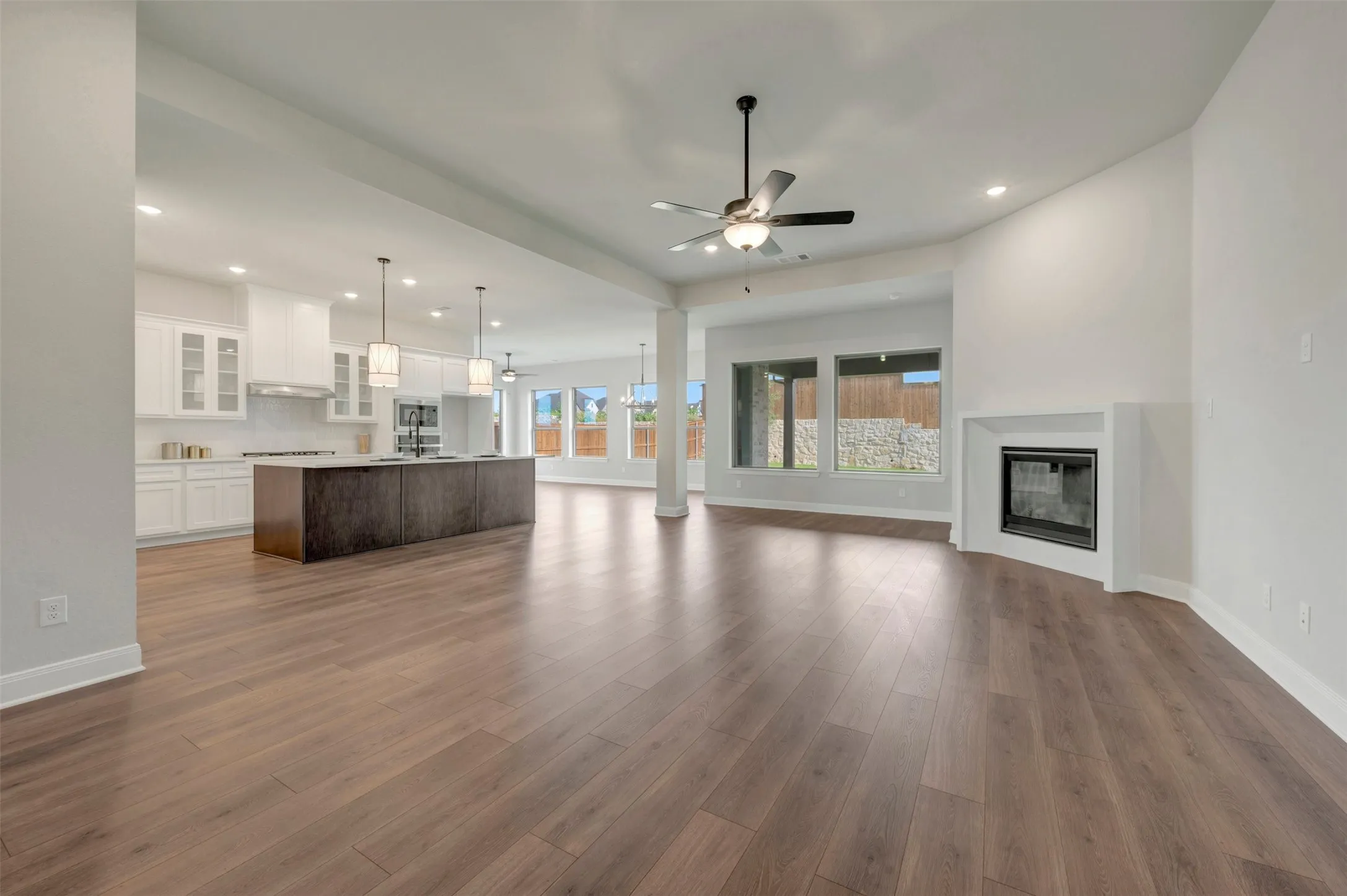 Expansive open-concept living area featuring wood-finish flooring, a modern fireplace, and recessed lighting