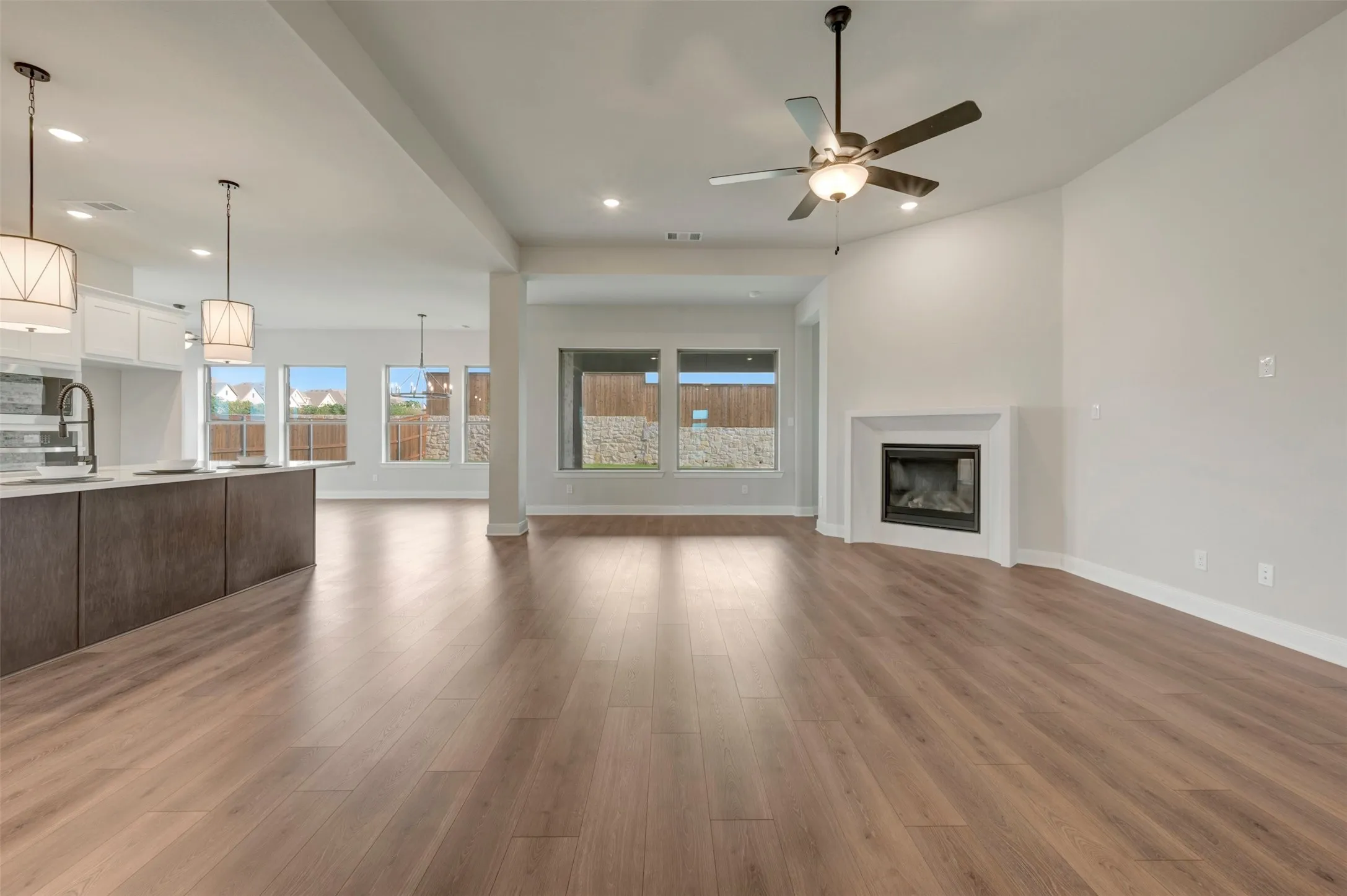Open-concept living space featuring wood-finish flooring, a contemporary fireplace, and a ceiling fan