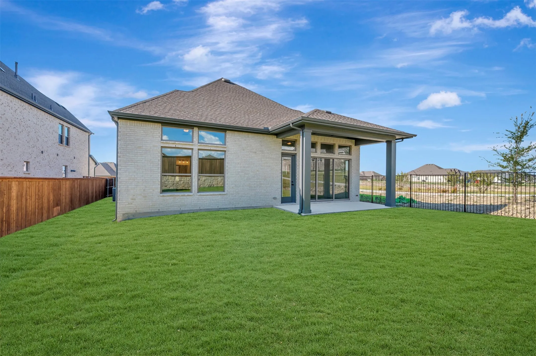 Expansive green lawn surrounds a light-colored brick exterior